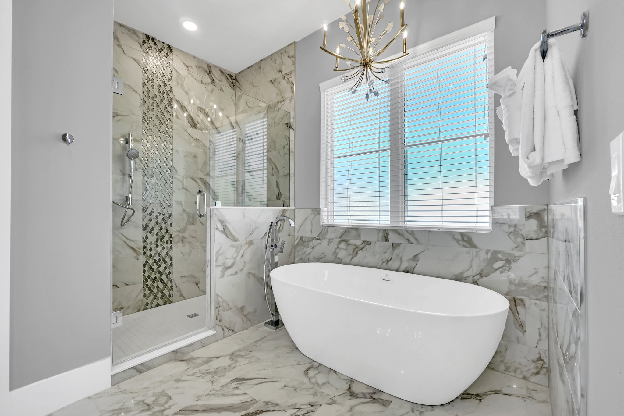 Guest bath with a freestanding soaking tub and a marble shower