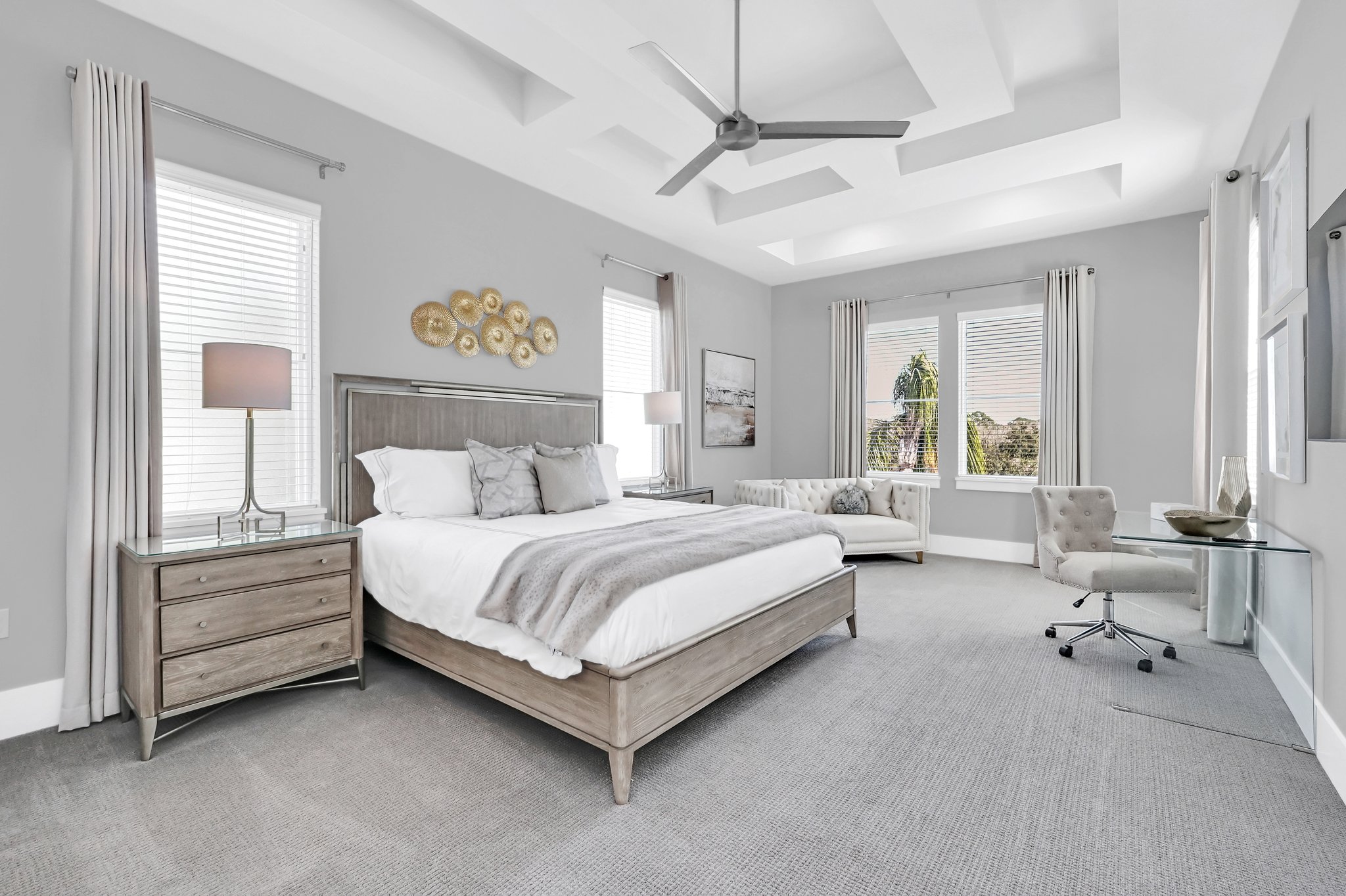 Spacious guest suite with a coffered ceiling, sitting sofa, and desk