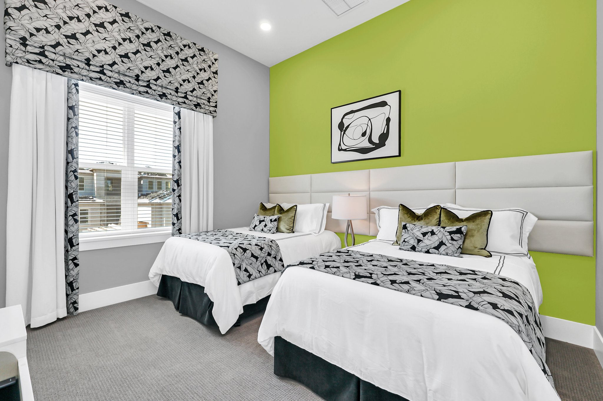 Guest bedroom with two queen beds and a lime-green accent wall