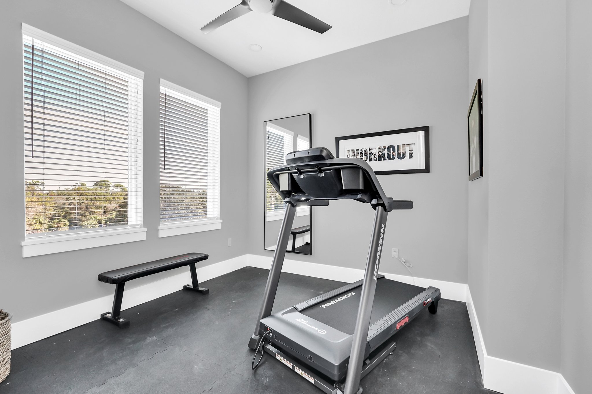 Fitness room with a treadmill, a weight bench, and a wall-mounted TV