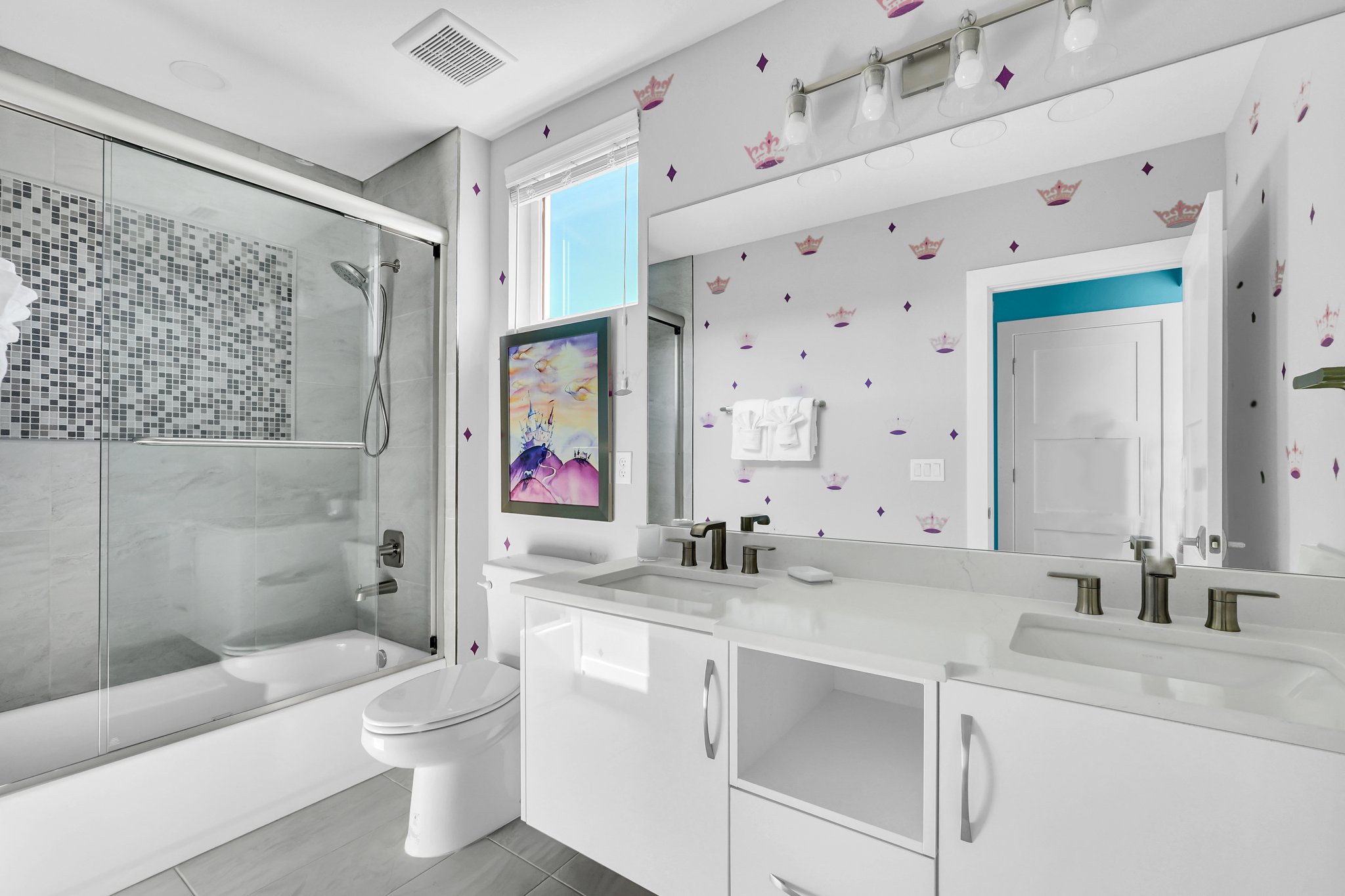 Princess suite bathroom with crown-print walls, a tub-shower, and a mosaic accent