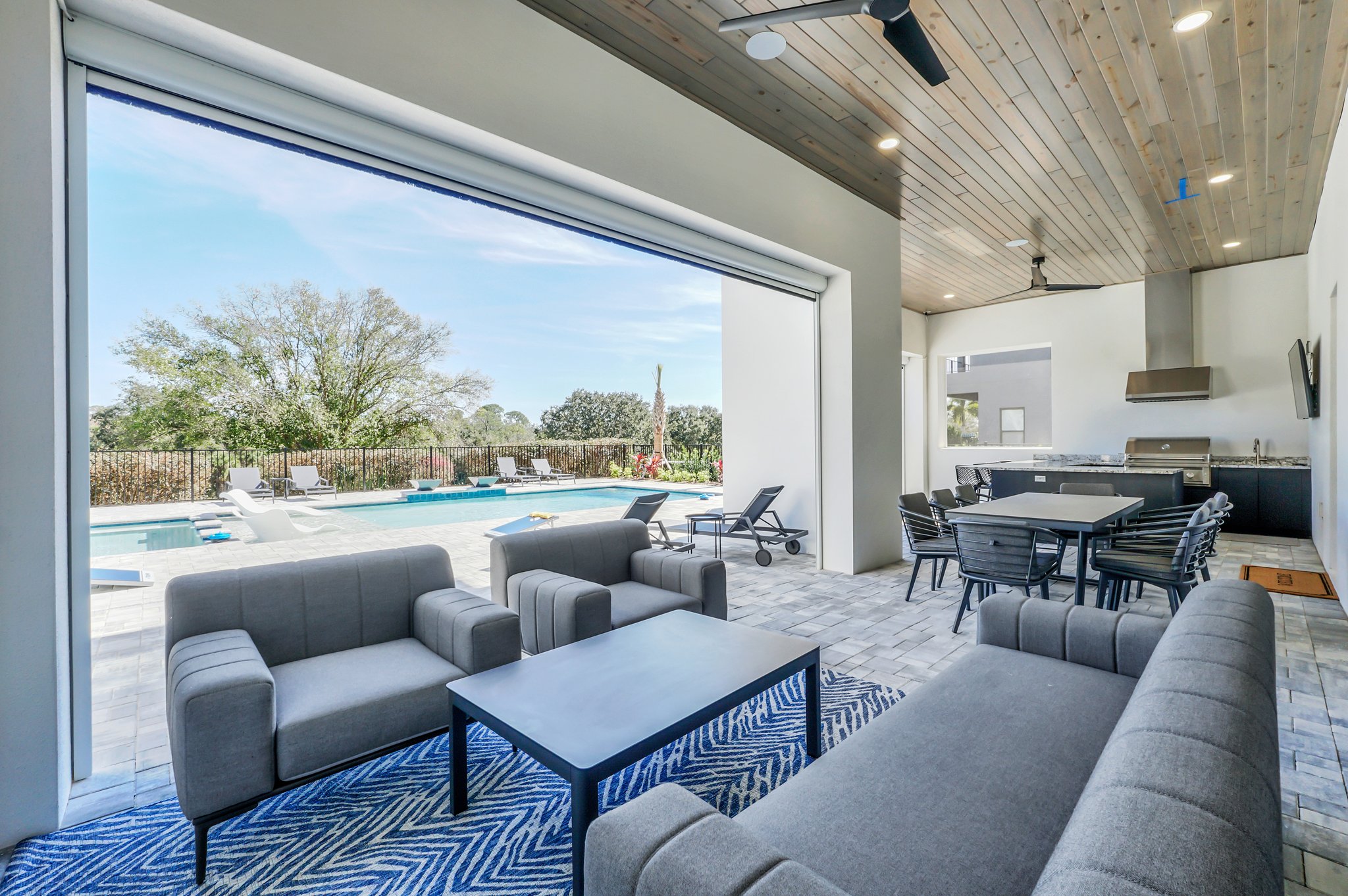 Covered lanai lounge opening through pocketing sliders to the pool deck