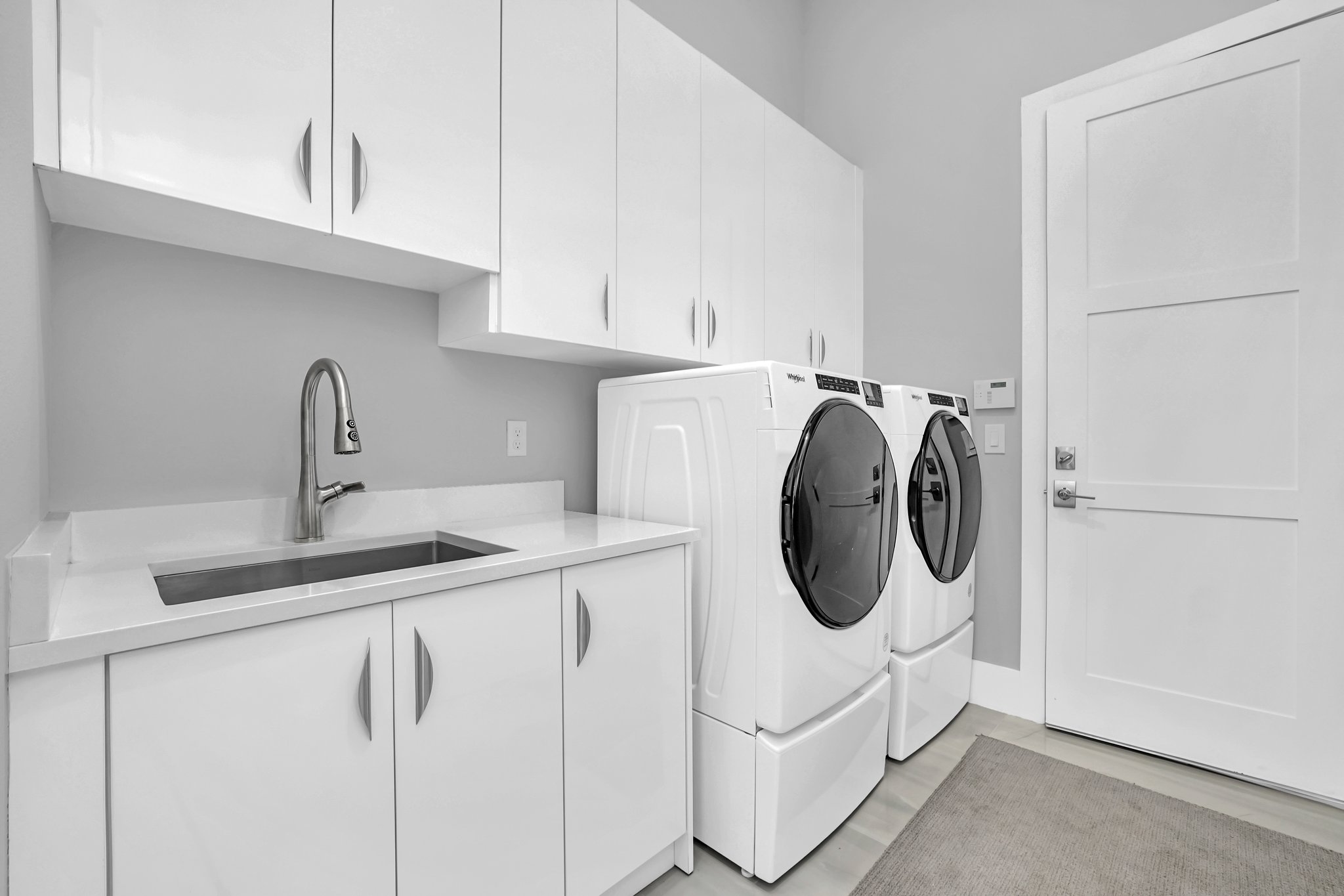 Laundry room with a side-by-side washer and dryer, a utility sink, and white cabinetry