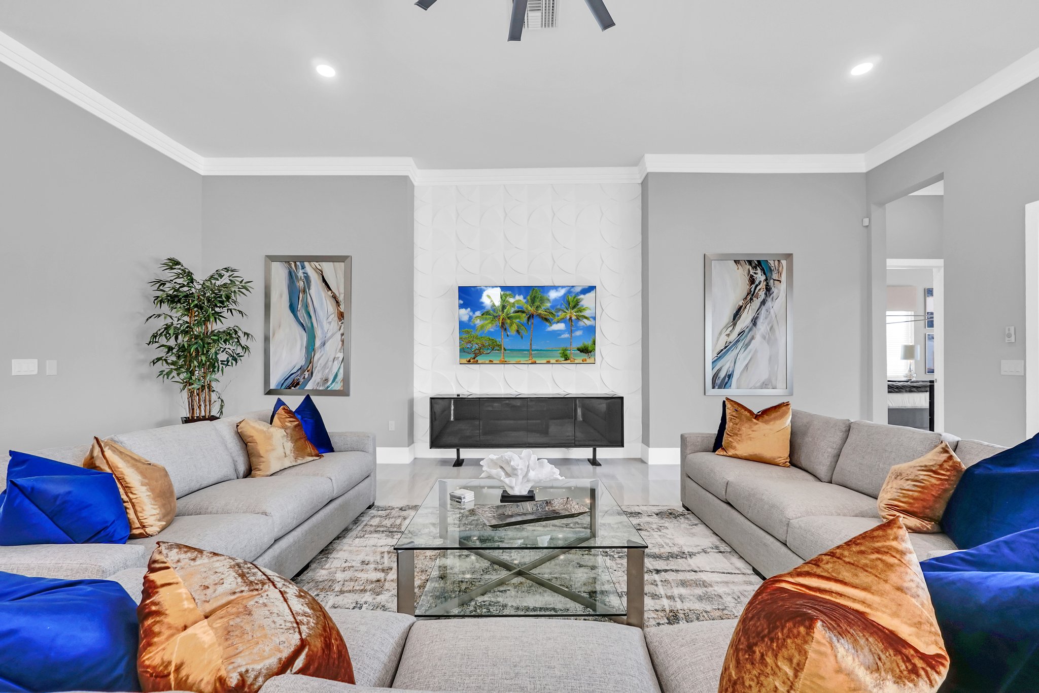 Family lounge with facing grey sectionals and a palm-print media wall