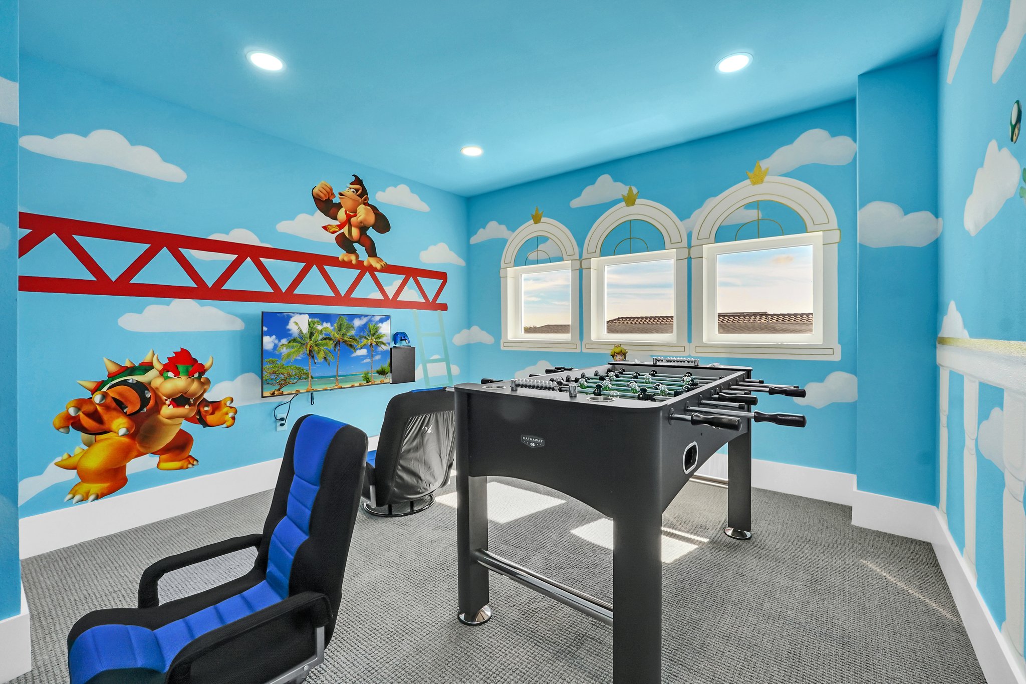 Super Mario-themed game room with a hand-painted sky-and-characters mural and a foosball table