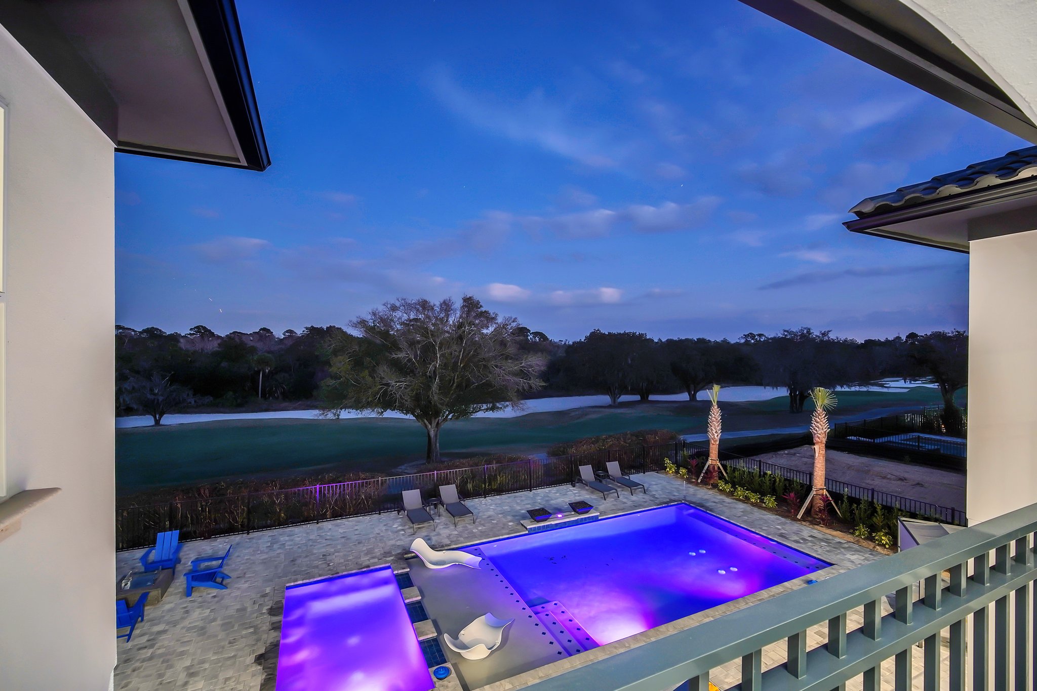 Resort pool and spa glowing purple at twilight over the fairway
