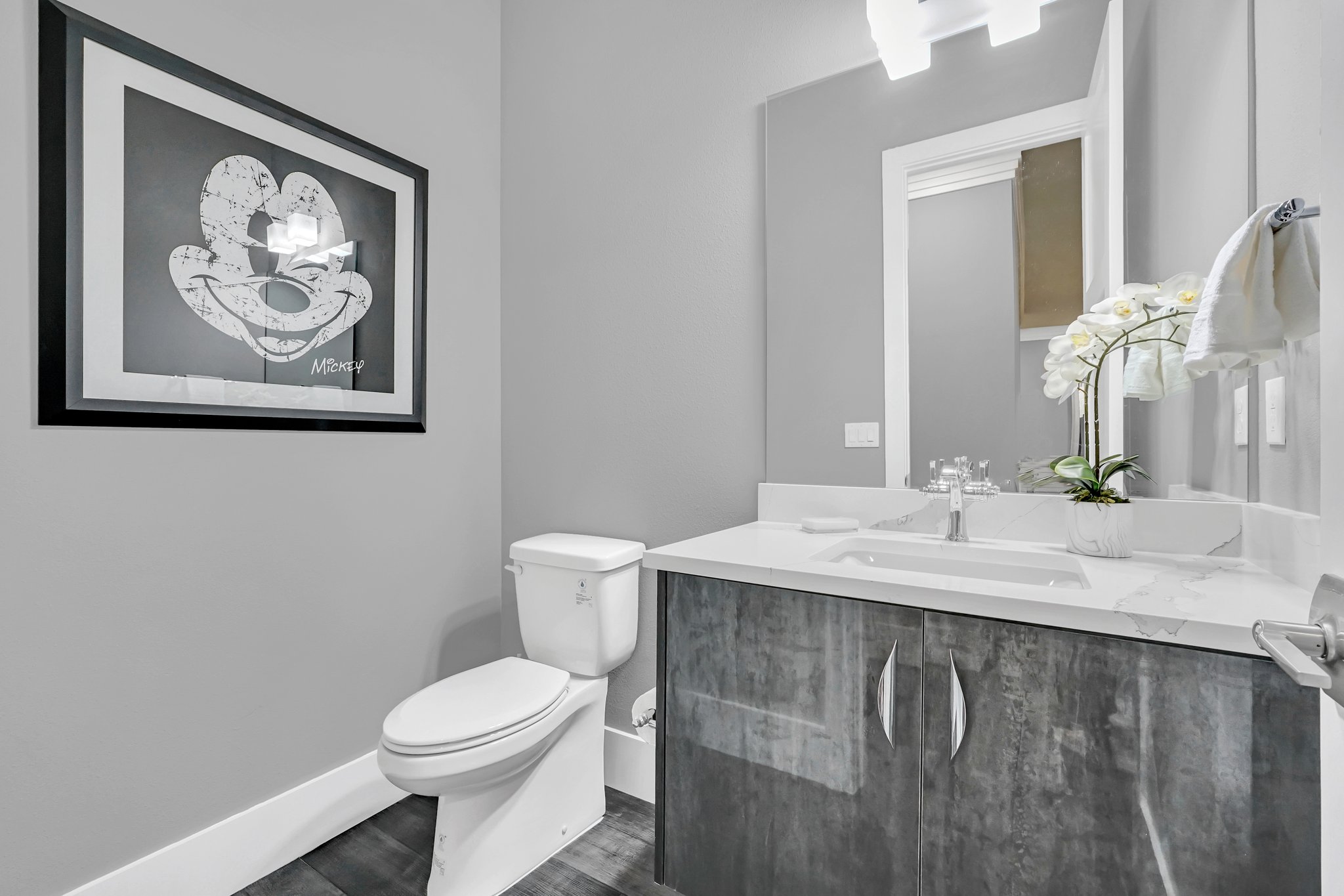Powder room with a charcoal floating vanity, framed art, and a marble-look wall