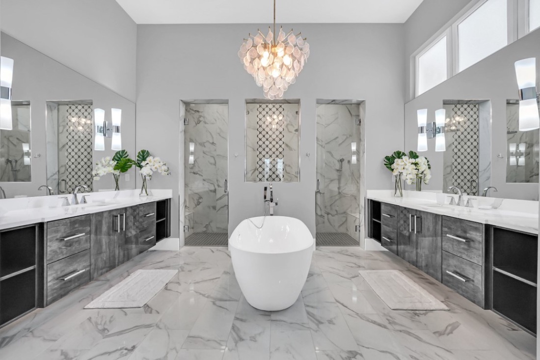 Primary bath with a freestanding tub, dual marble vanities, and a capiz chandelier