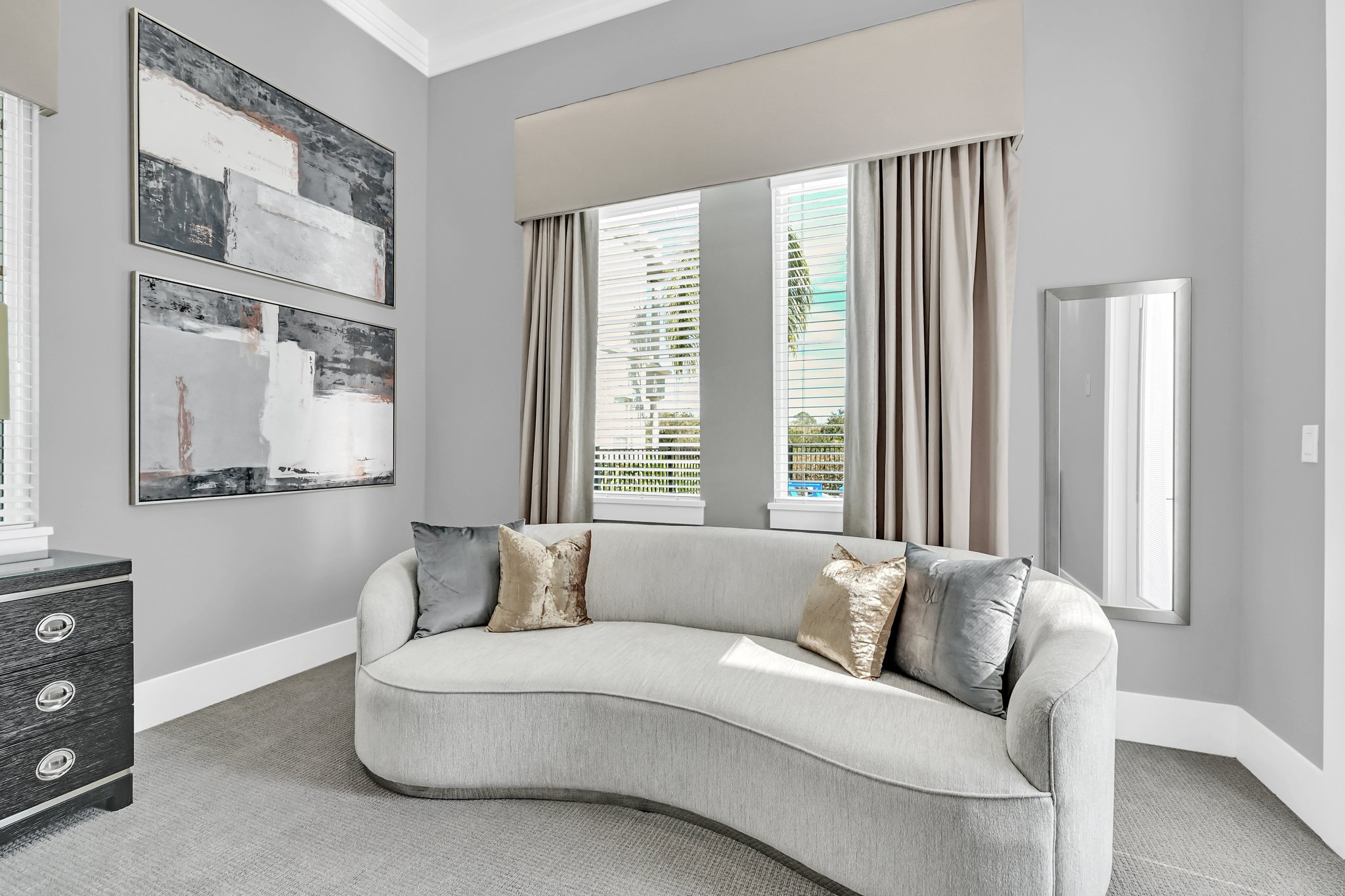 Primary suite sitting area with a curved cream sofa and abstract art