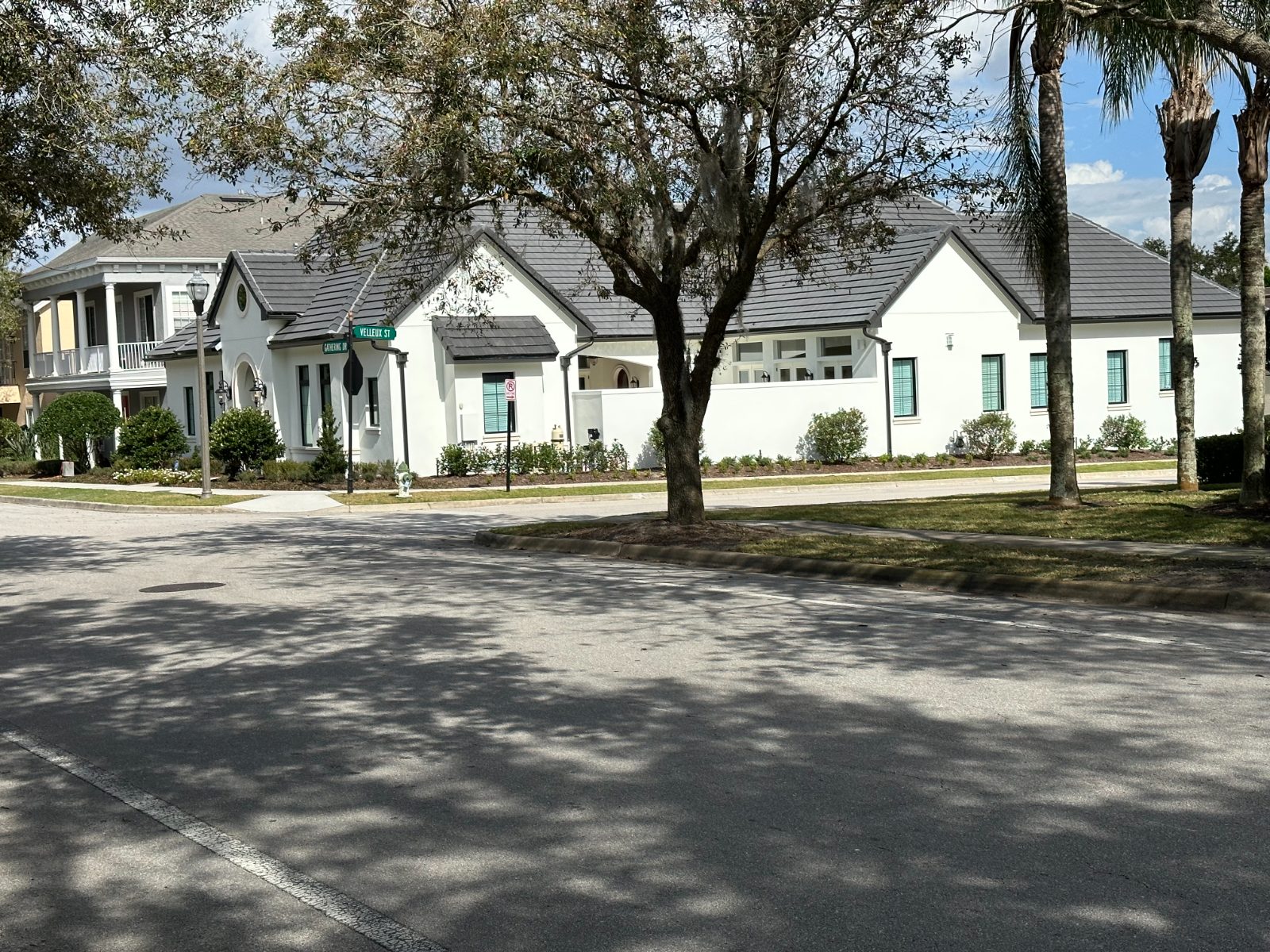 French Country — white traditional home with tile roof on a corner lot