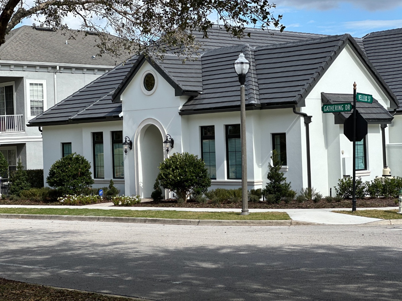French Country — traditional white home with a tile roof and arched entry