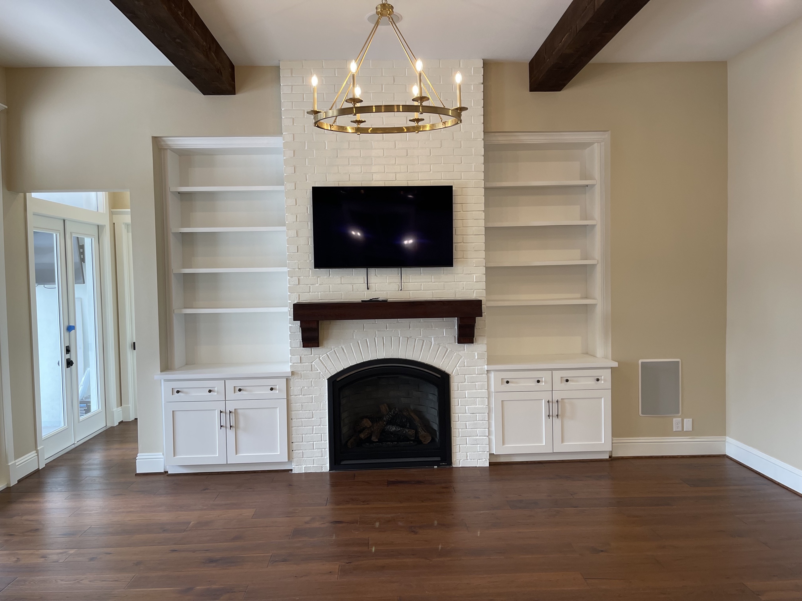 Painted-brick hearth flanked by built-in shelving beneath a brass chandelier