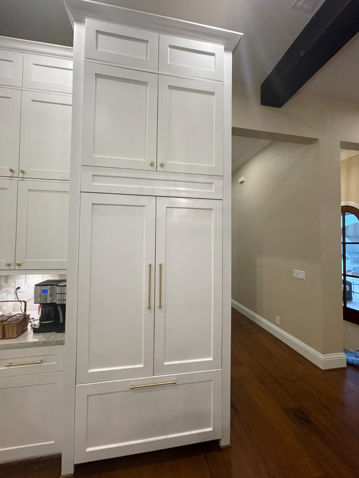 Floor-to-ceiling painted cabinetry beneath a dark beam