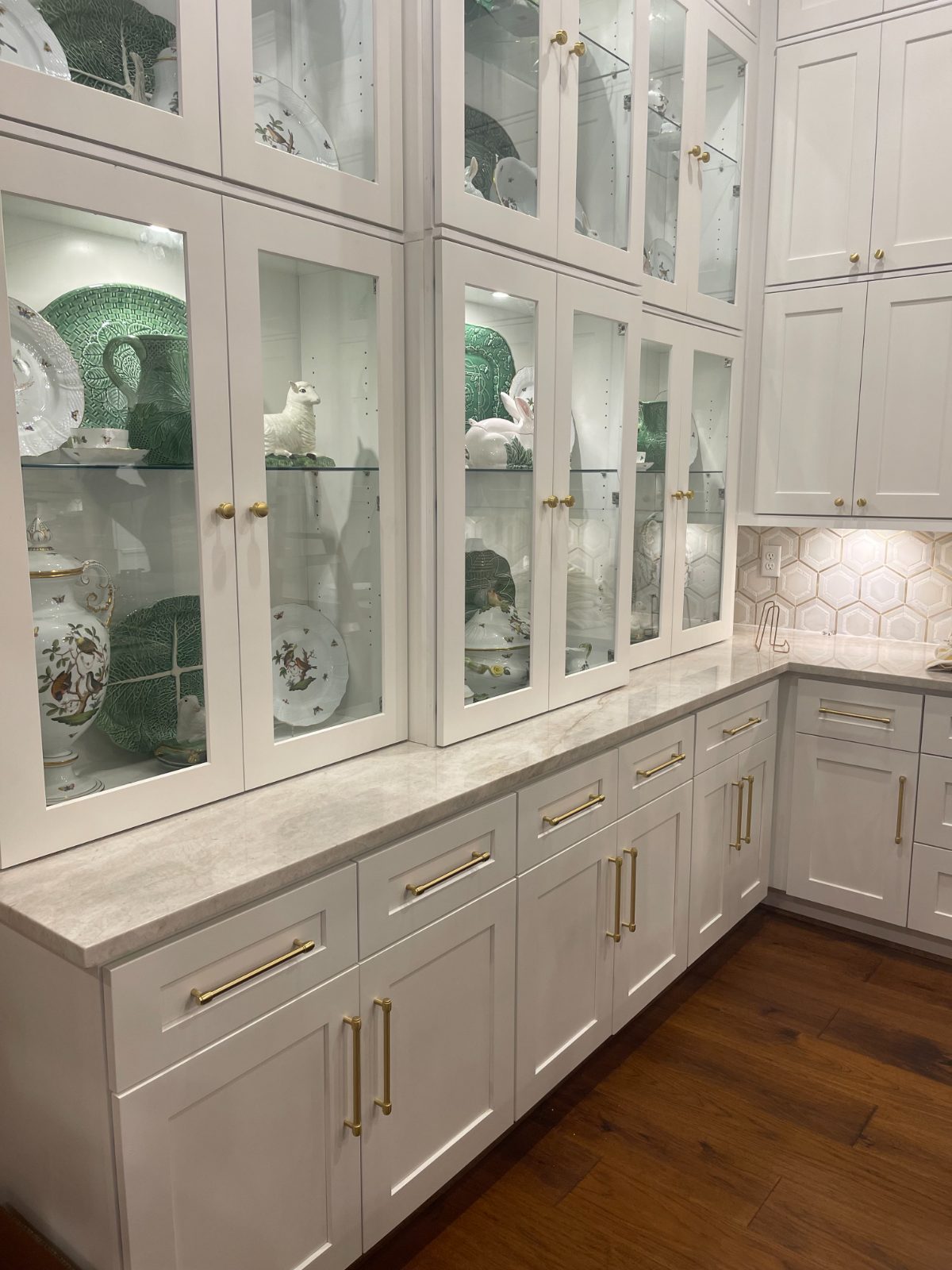 Glass-front cabinetry with displayed china and marble counter