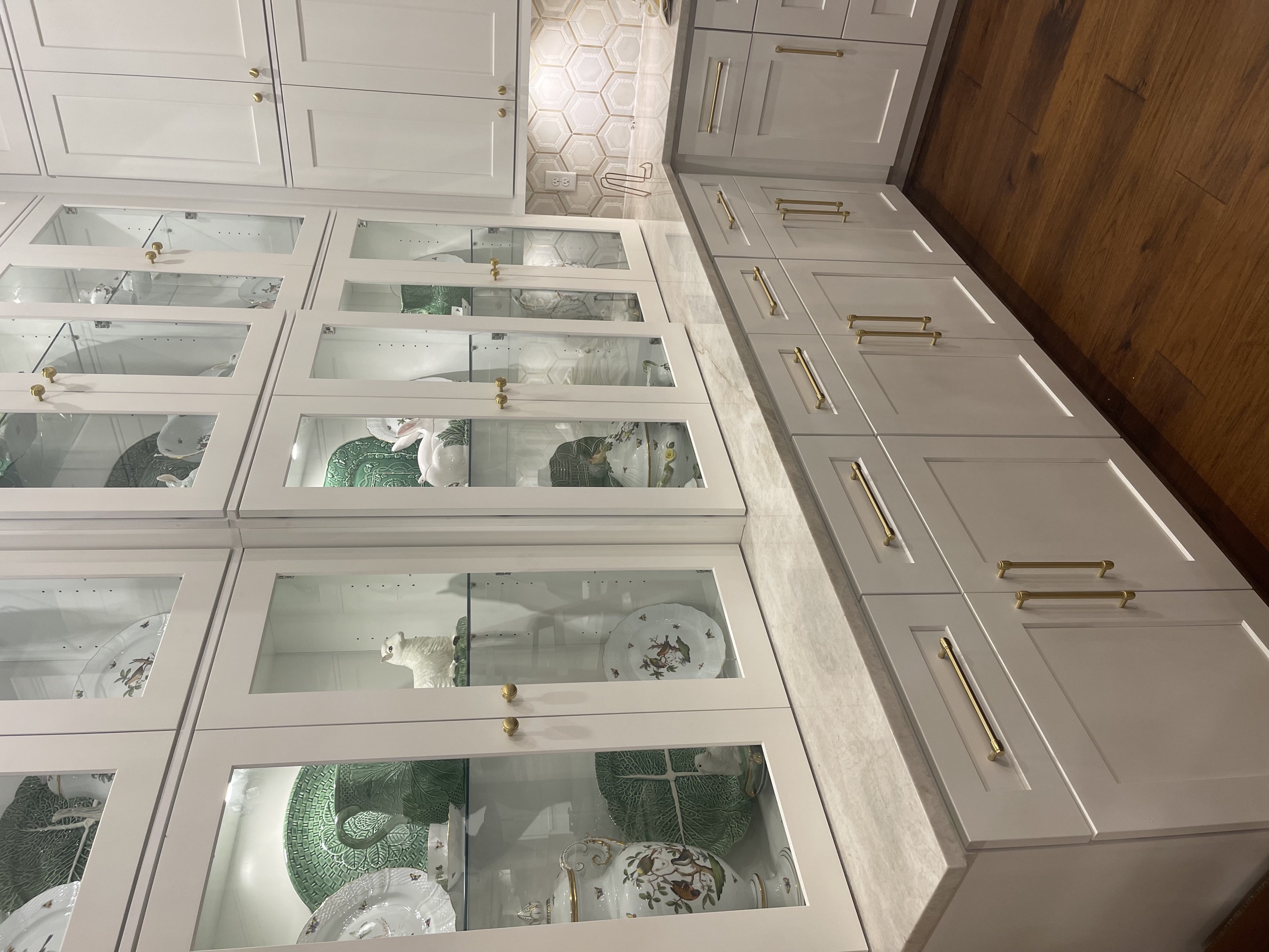 Butler's pantry with glass-front cabinetry, marble counter, and brass hardware