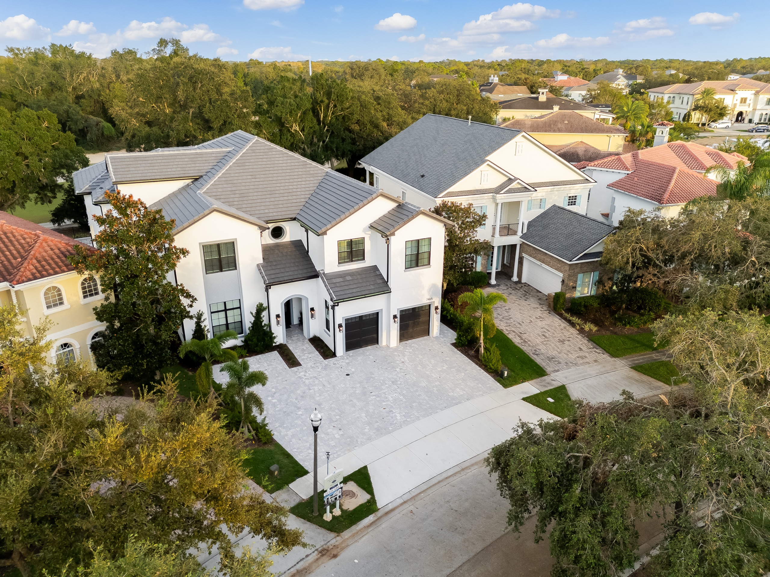 Aerial of the front elevation and paver drive among the oaks