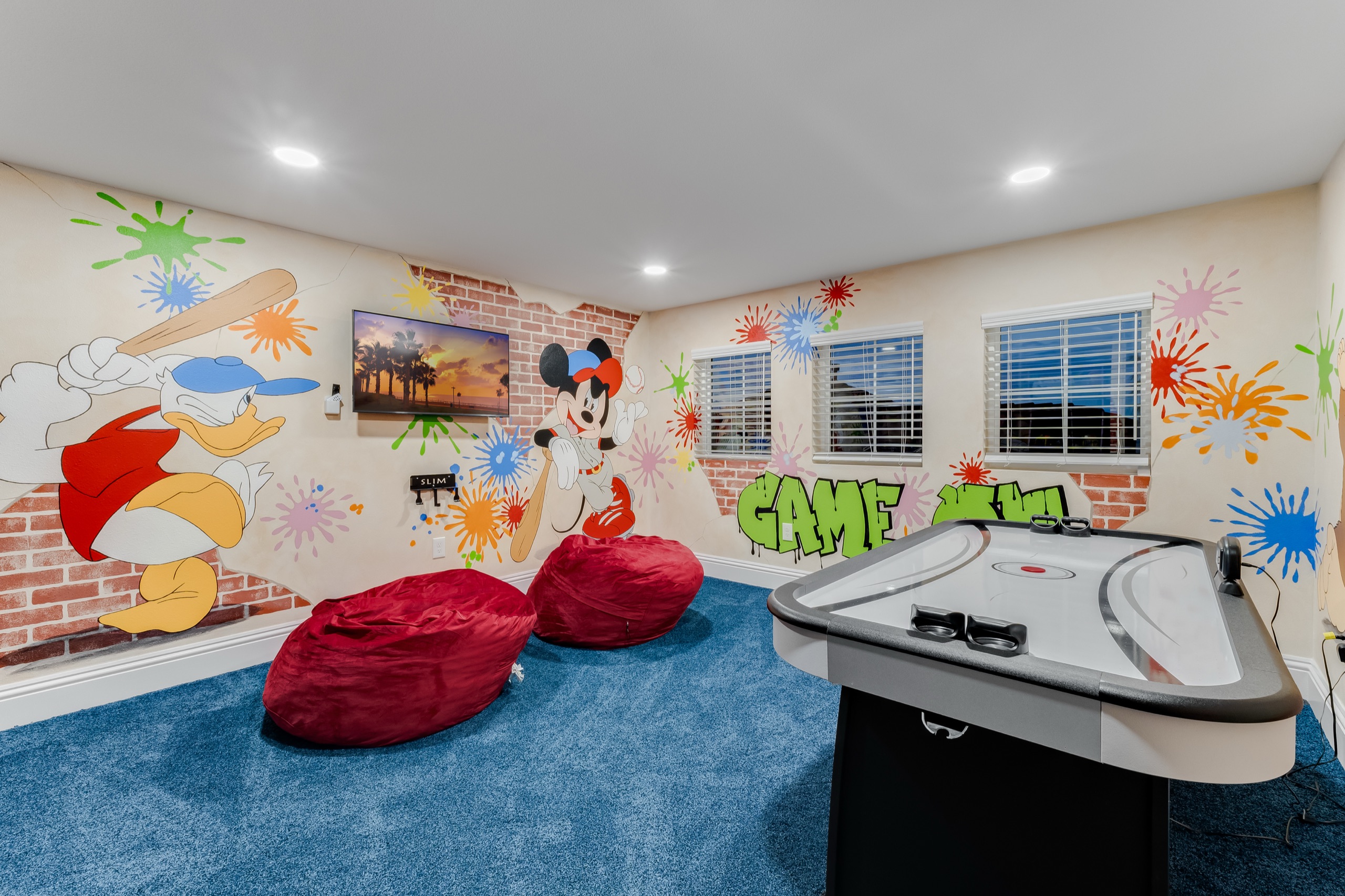 Kids' arcade and game room with air hockey, splatter murals, and bean bags