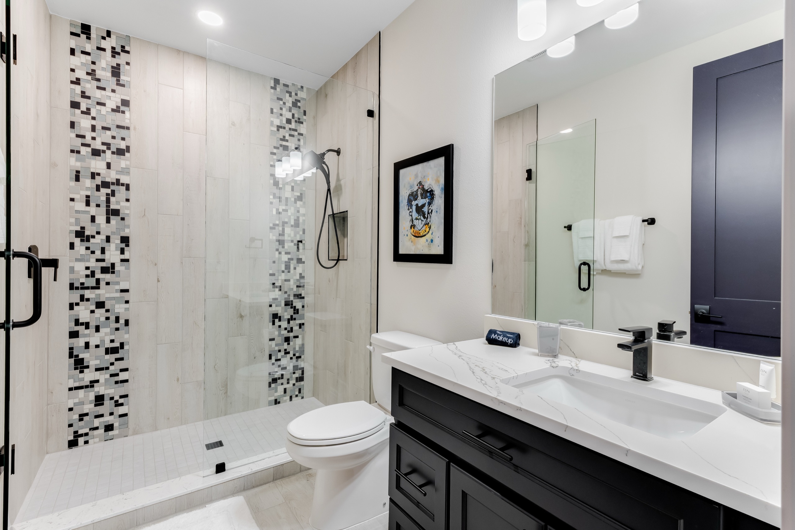 The castle bunk room's bath with a black-and-white tiled shower and a dark vanity