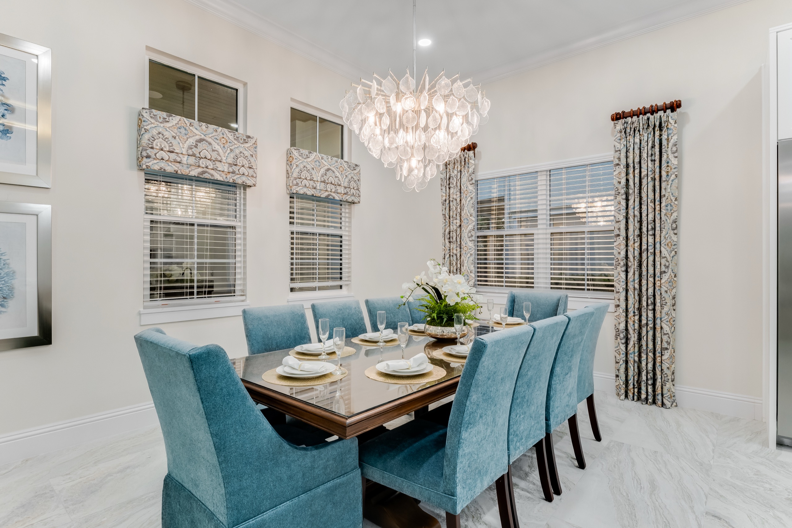 Formal dining room with blue chairs and a capiz-shell chandelier