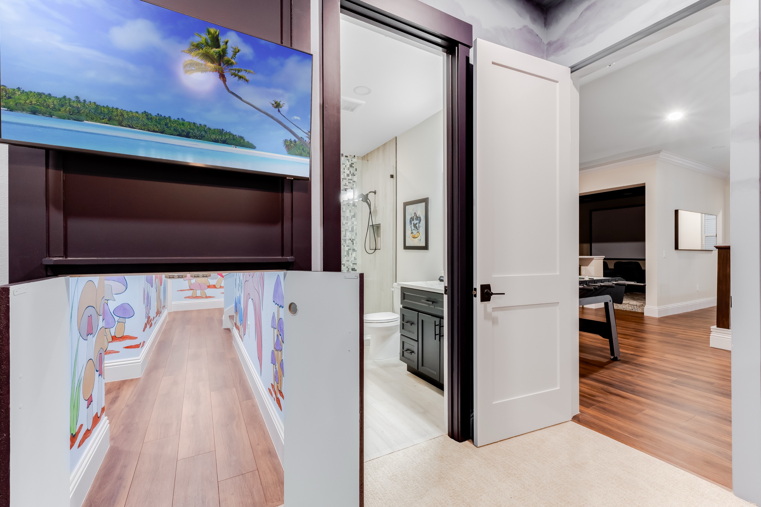 The hidden door to the kids' play space, set into a beach-mural TV wall