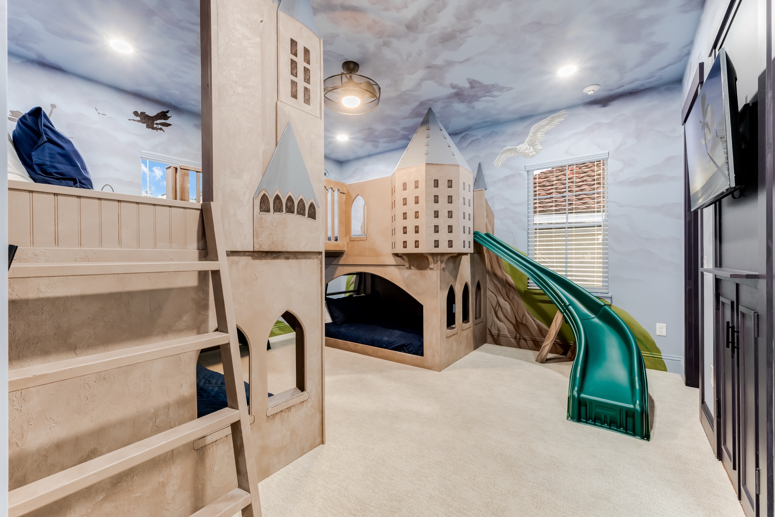 Wizard's-castle bunk room with a green slide and a cloud-painted ceiling