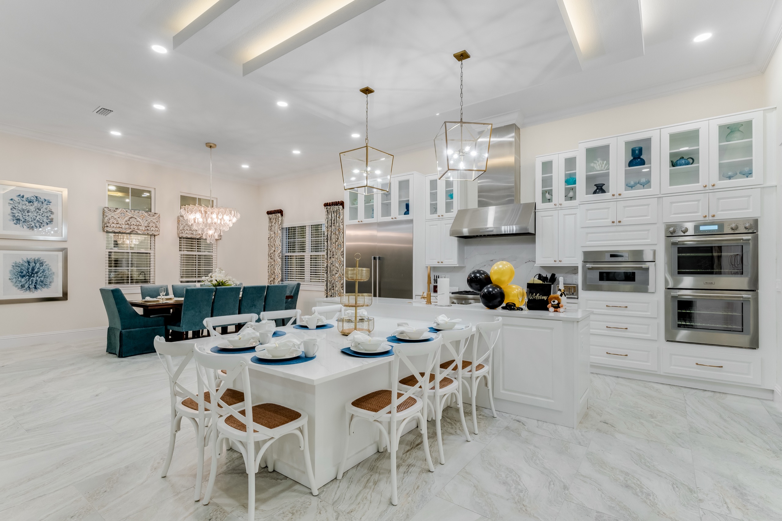 Kitchen and dining room seen wide with the marble island and the long dining table beyond