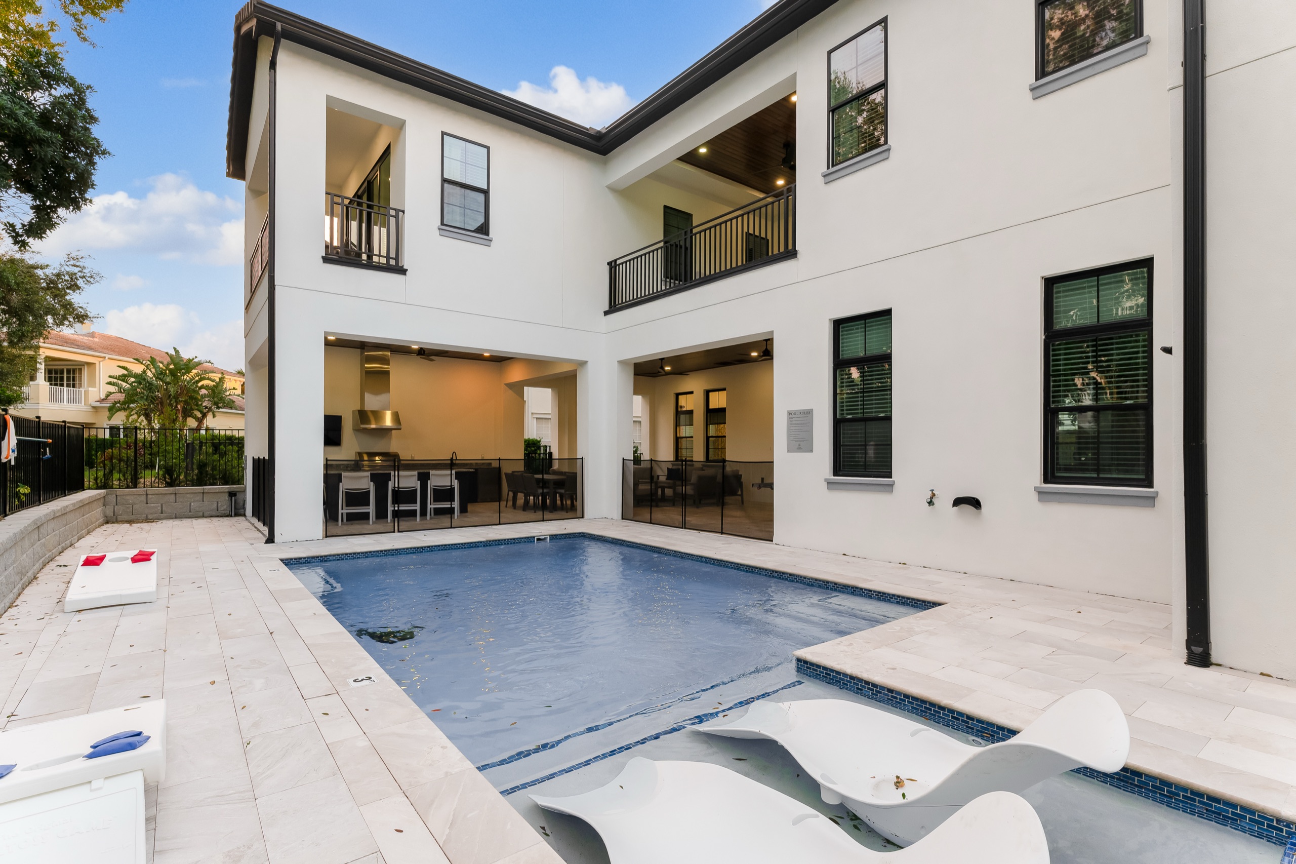 The pool and travertine deck by day with the rear elevation behind