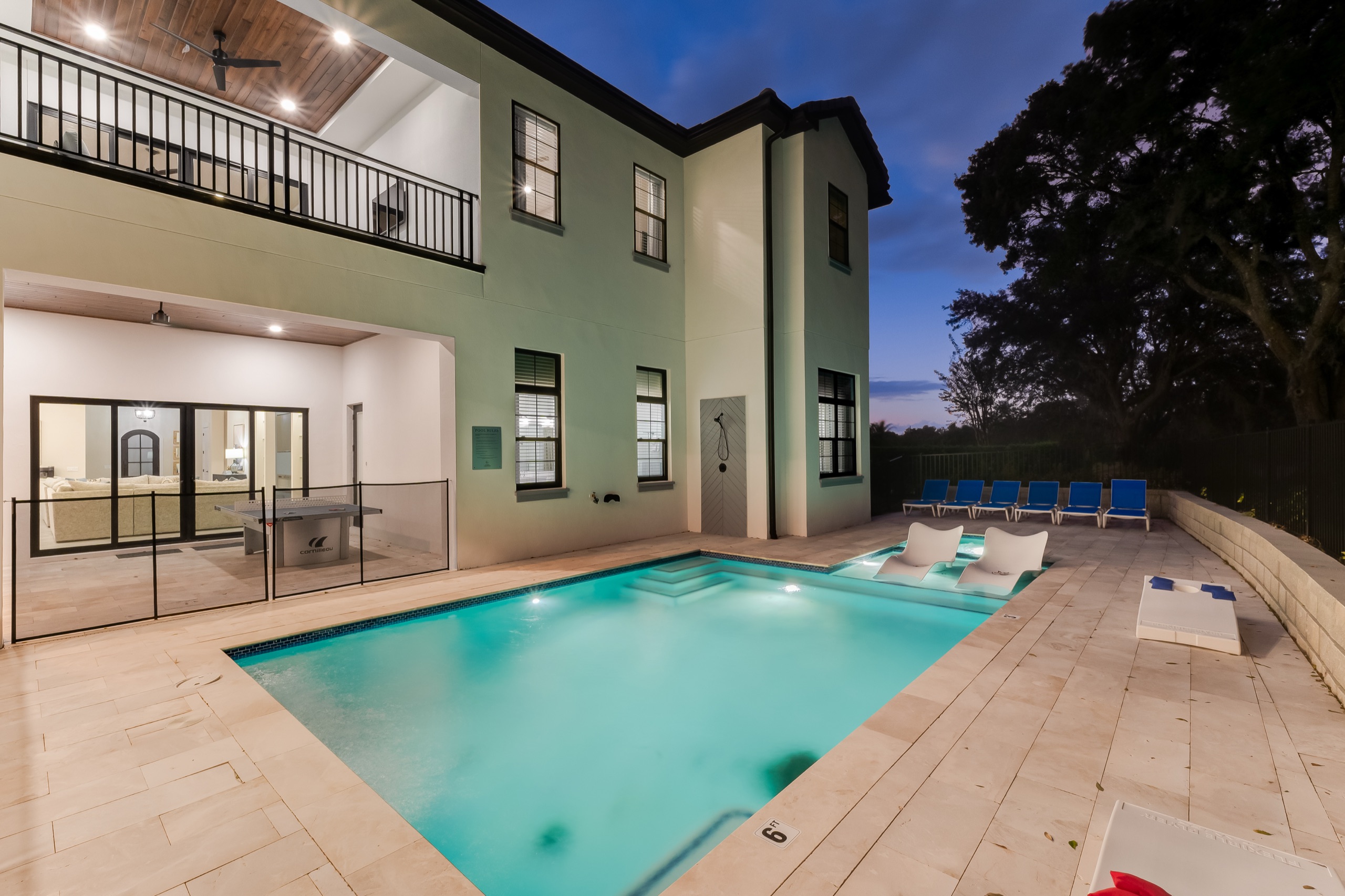 Gathering Loop — resort pool lit teal at twilight with the rear elevation behind