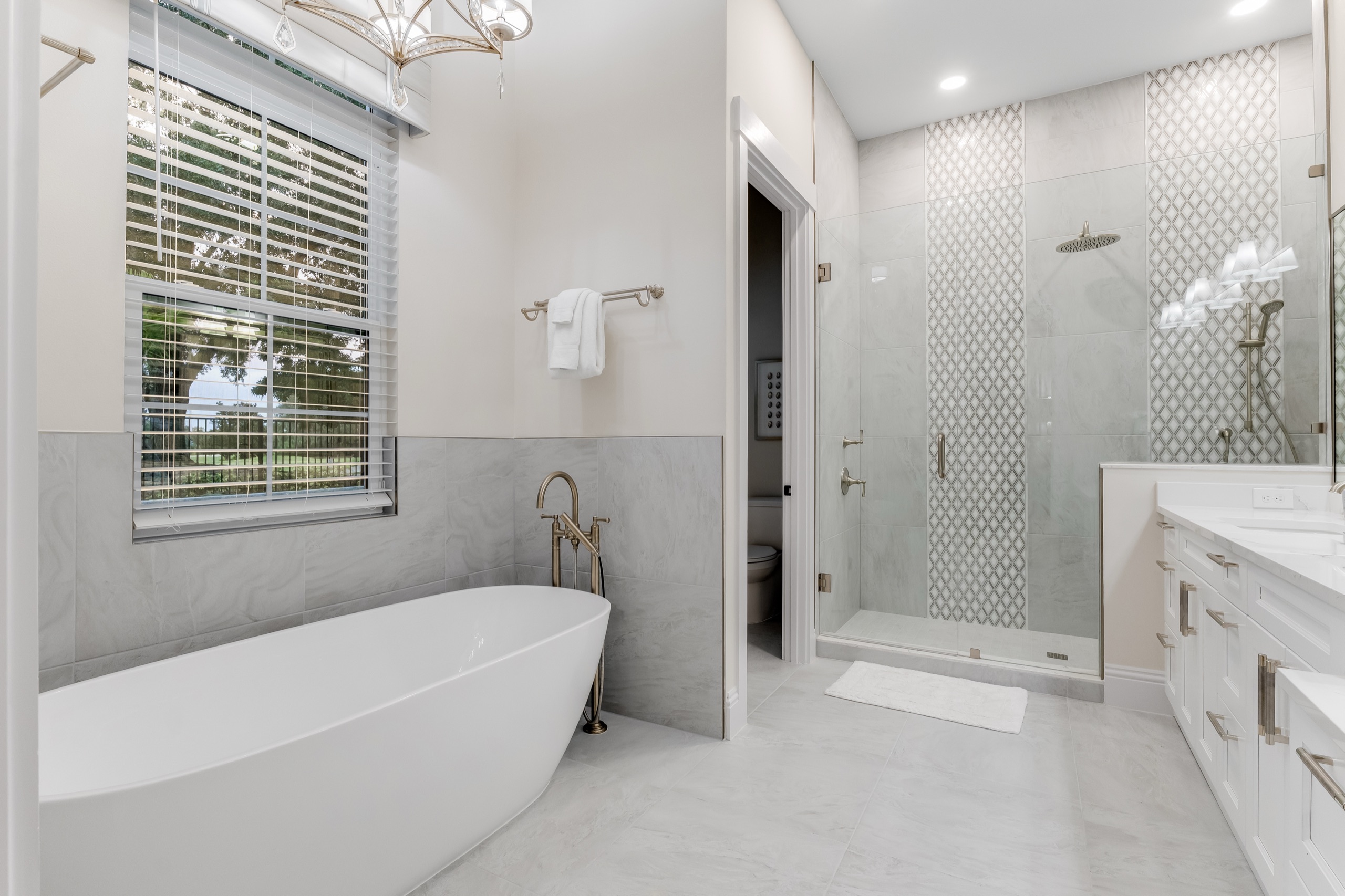 Suite bath with a freestanding soaking tub beside a glass shower