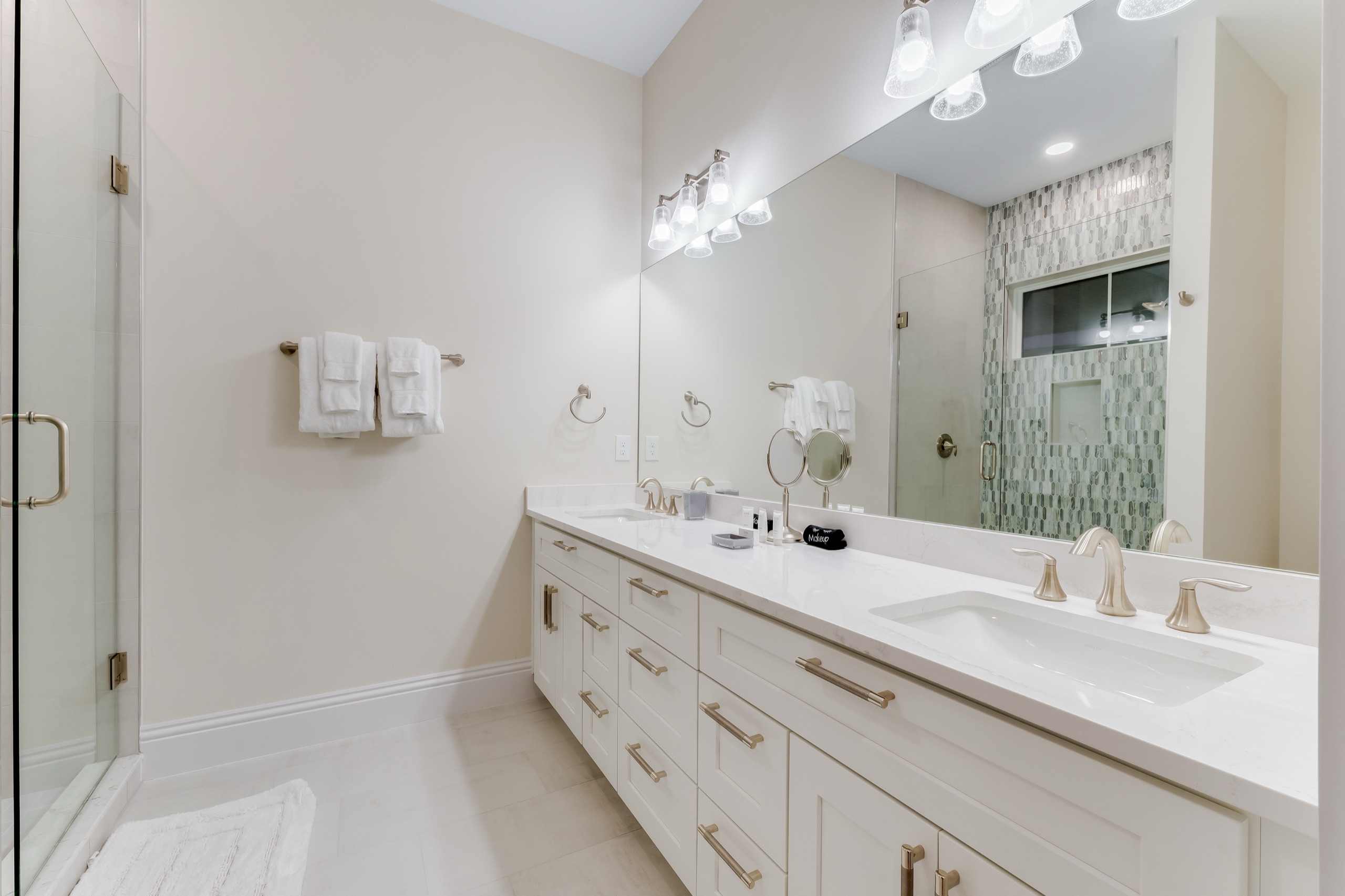 A second suite bath with a dual vanity and a glass walk-in shower