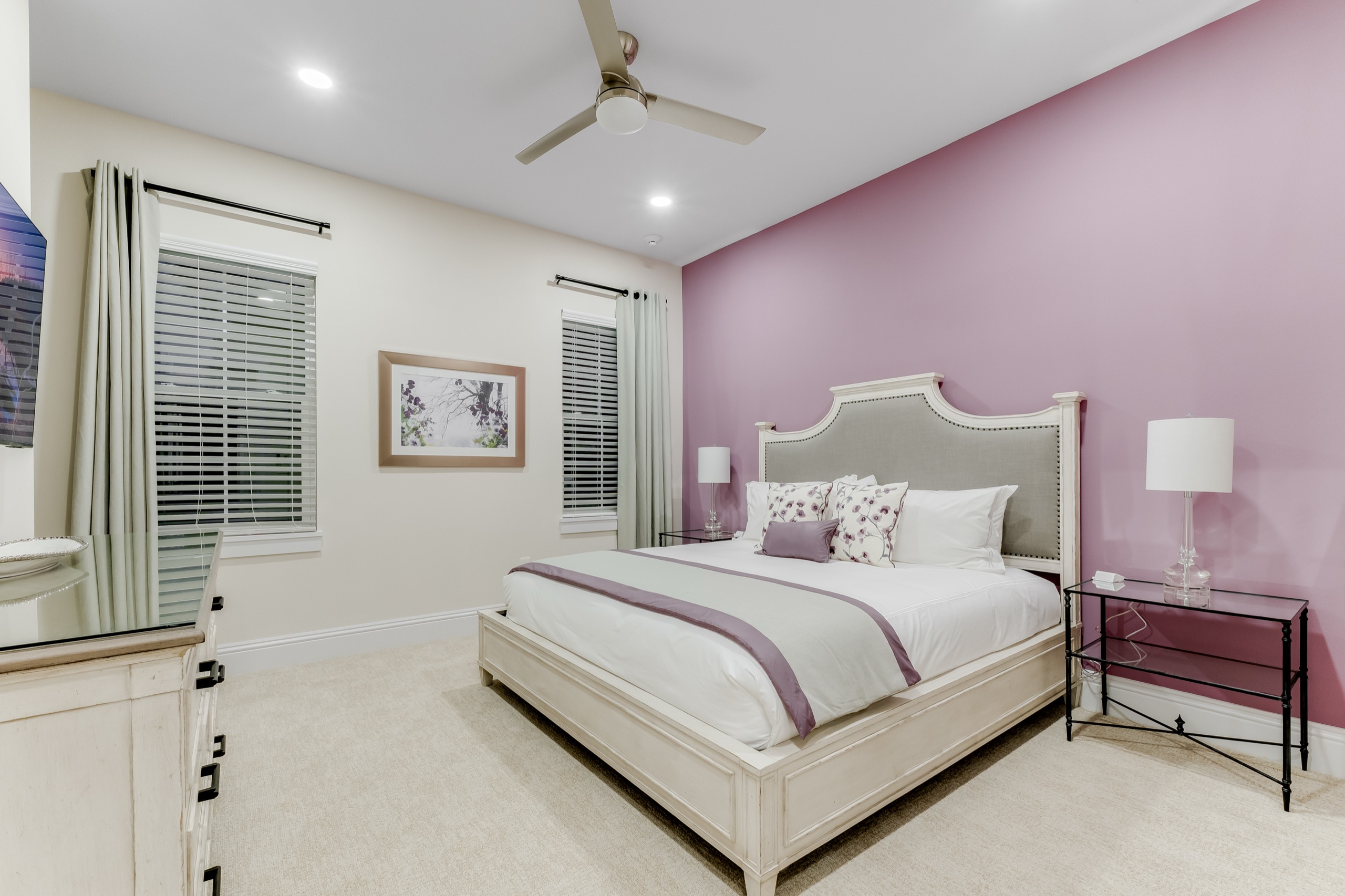 Guest suite with a mauve accent wall and a nailhead headboard