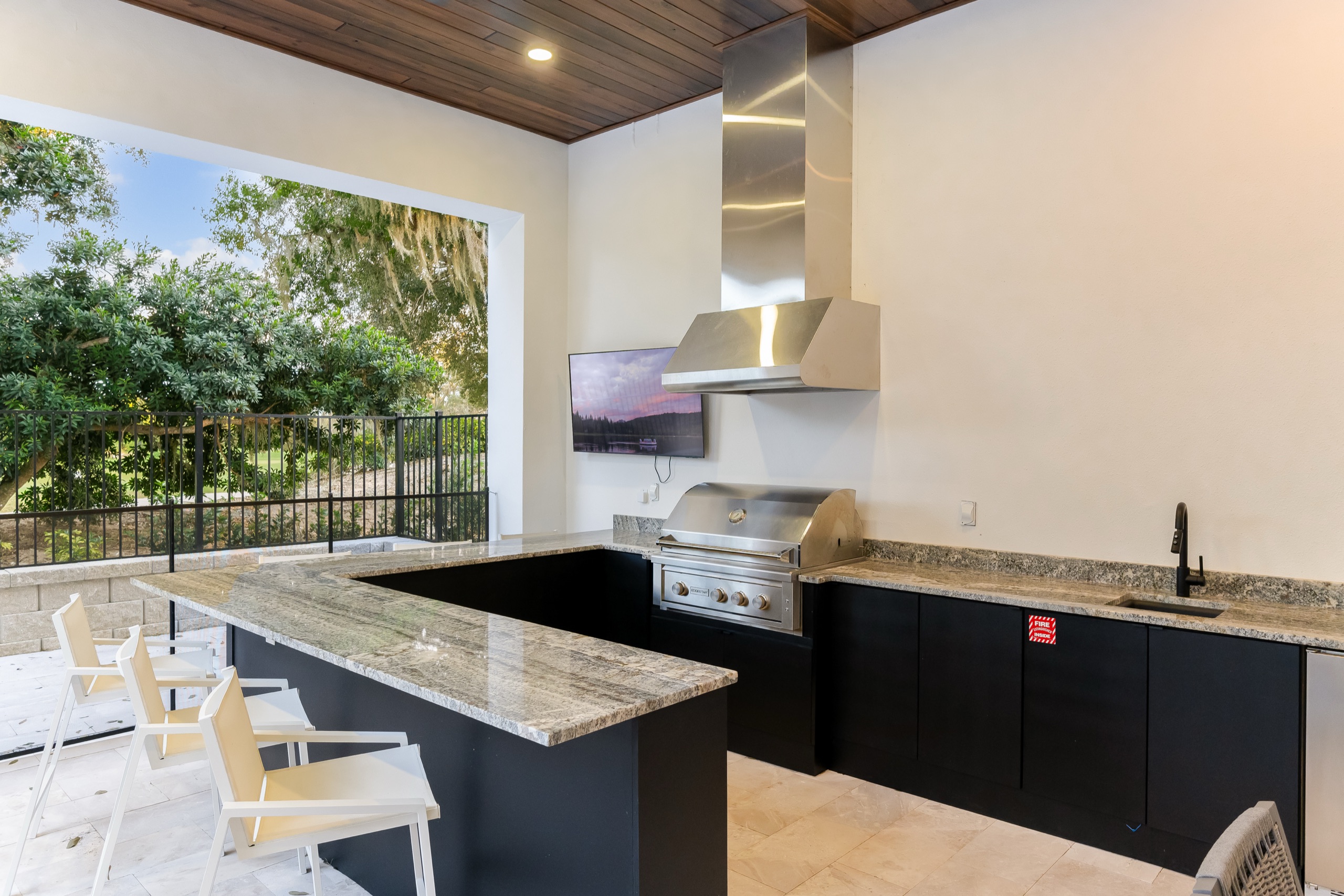 Summer kitchen with a built-in grill, granite bar, and a stainless hood