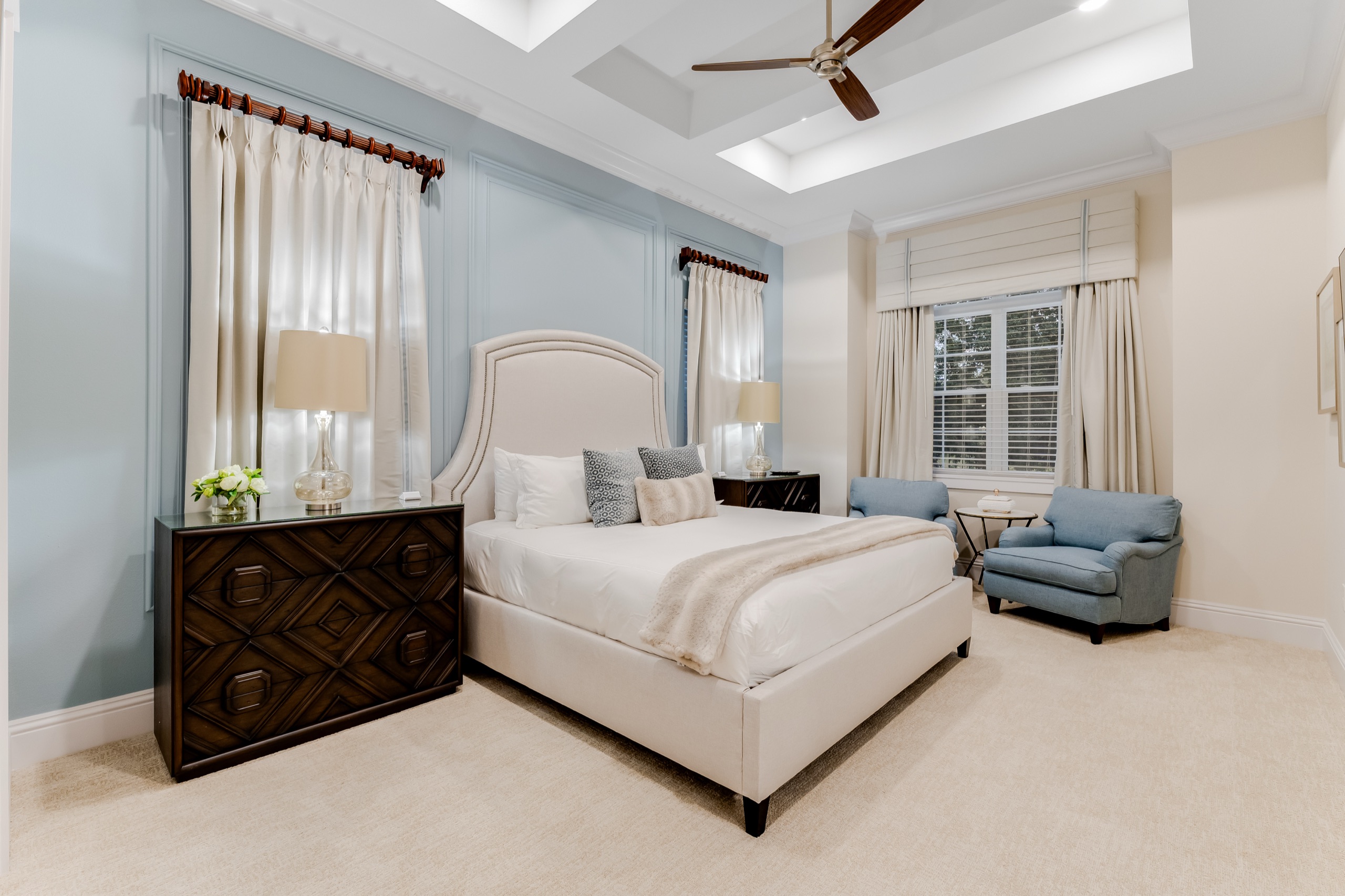 Upstairs suite with a pale-blue paneled wall, upholstered bed, and a sitting area