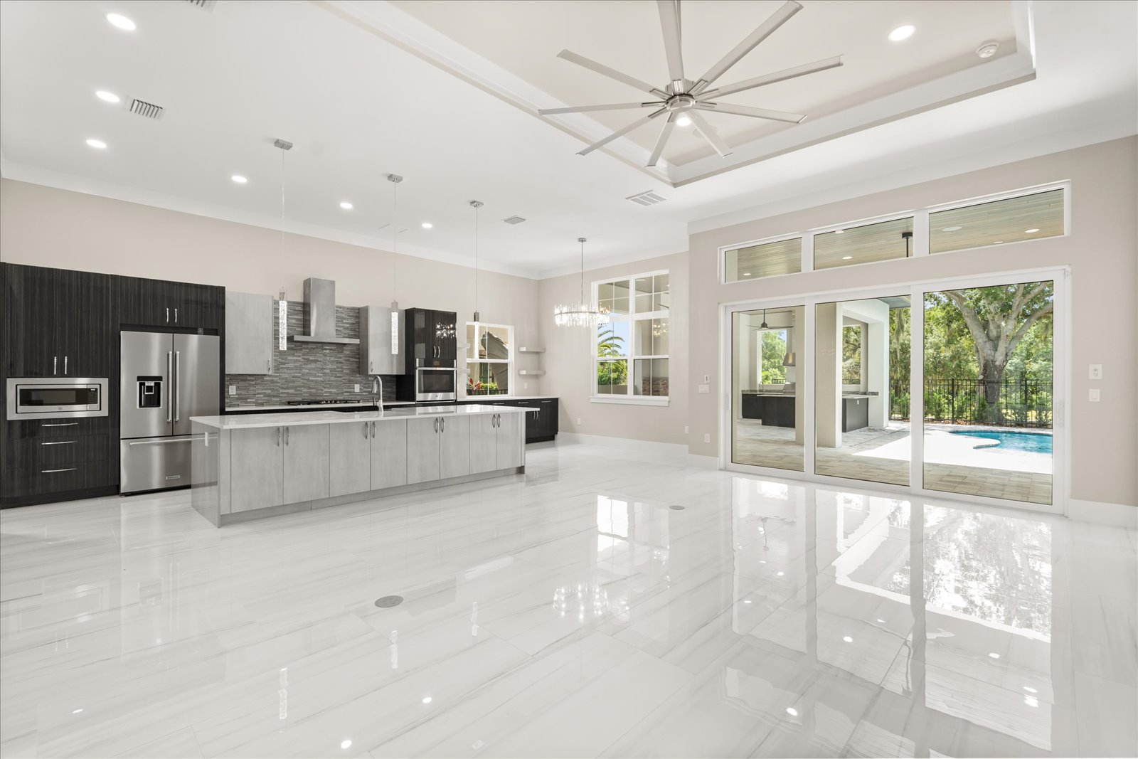 Kitchen and great room with marble floors and a wall of glass to the pool