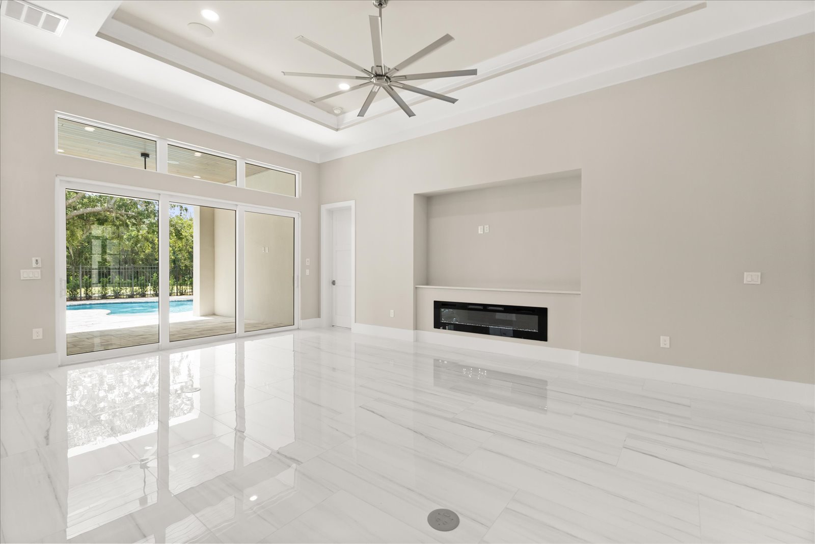 Great room with a linear fireplace and a wall of glass to the pool