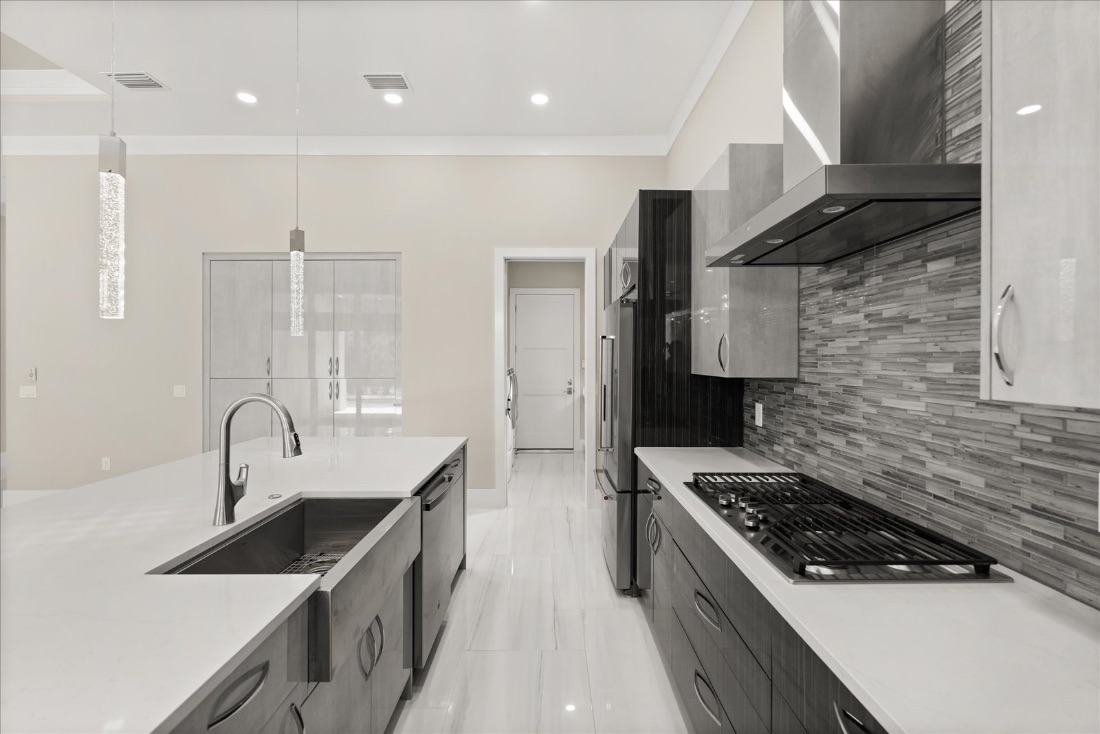 Farmhouse-sink island and a gas cooktop along the marble counter