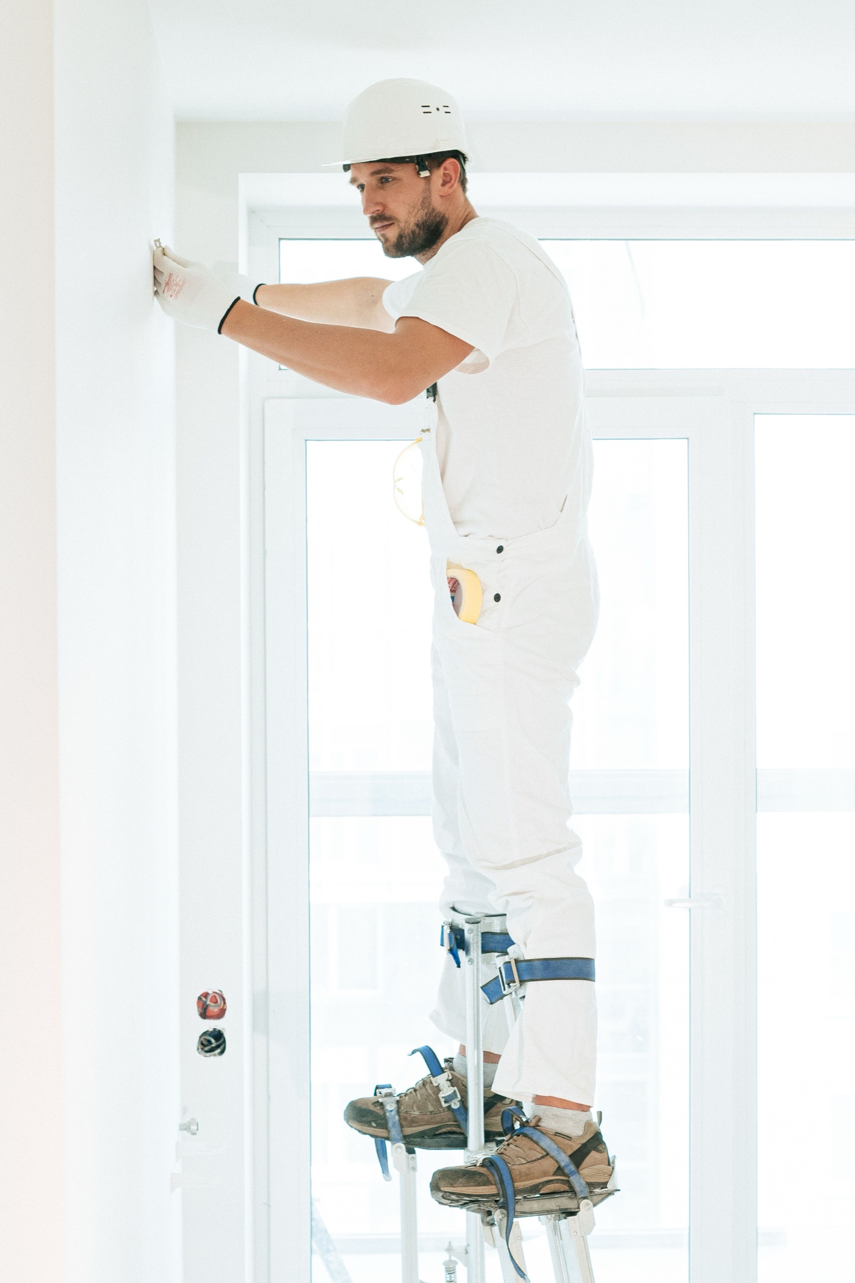 A painter on stilts finishing walls during the punch-list phase of a Liberty home