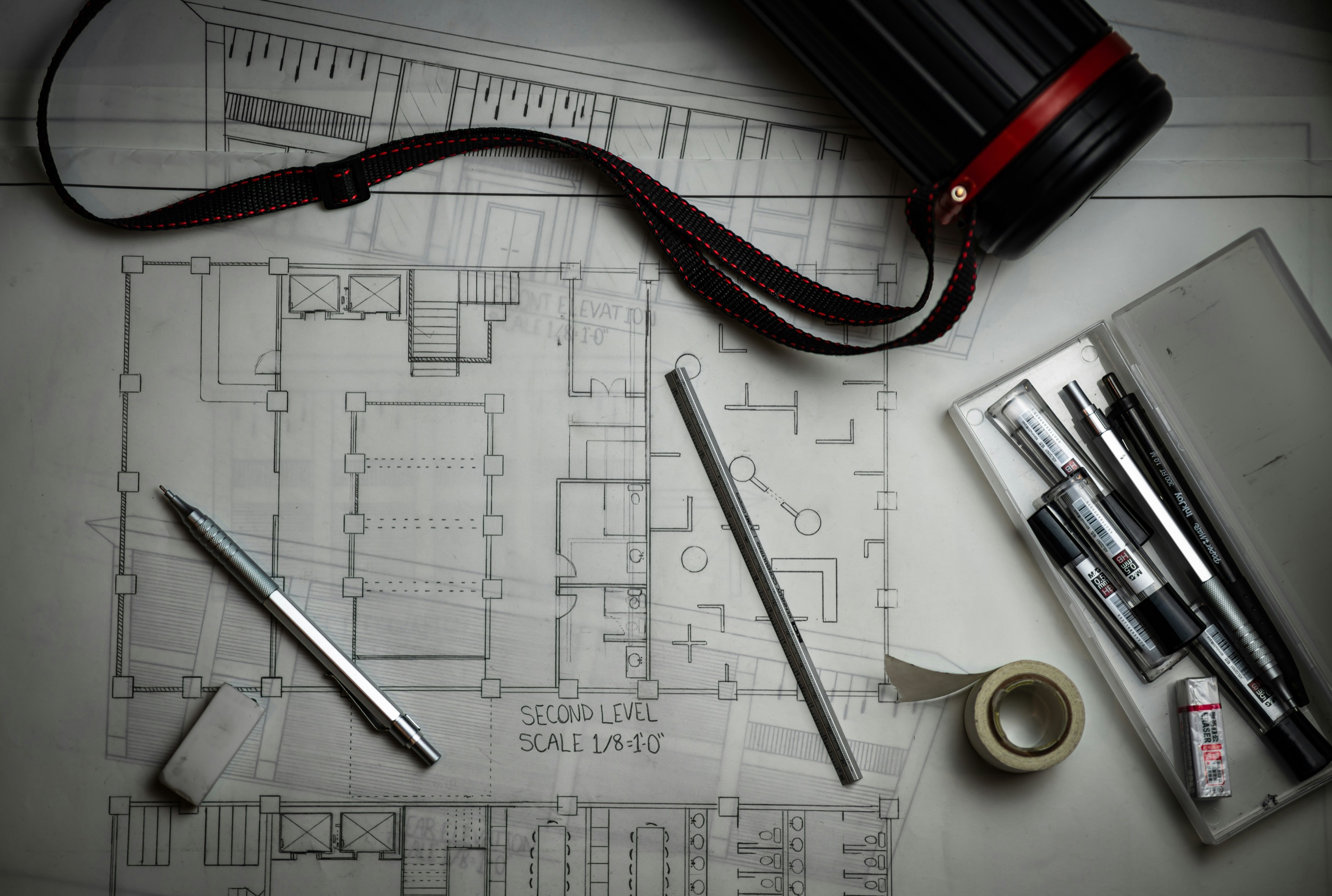 A hand-drafted floor plan with mechanical pencils, scale ruler, and drawing tools