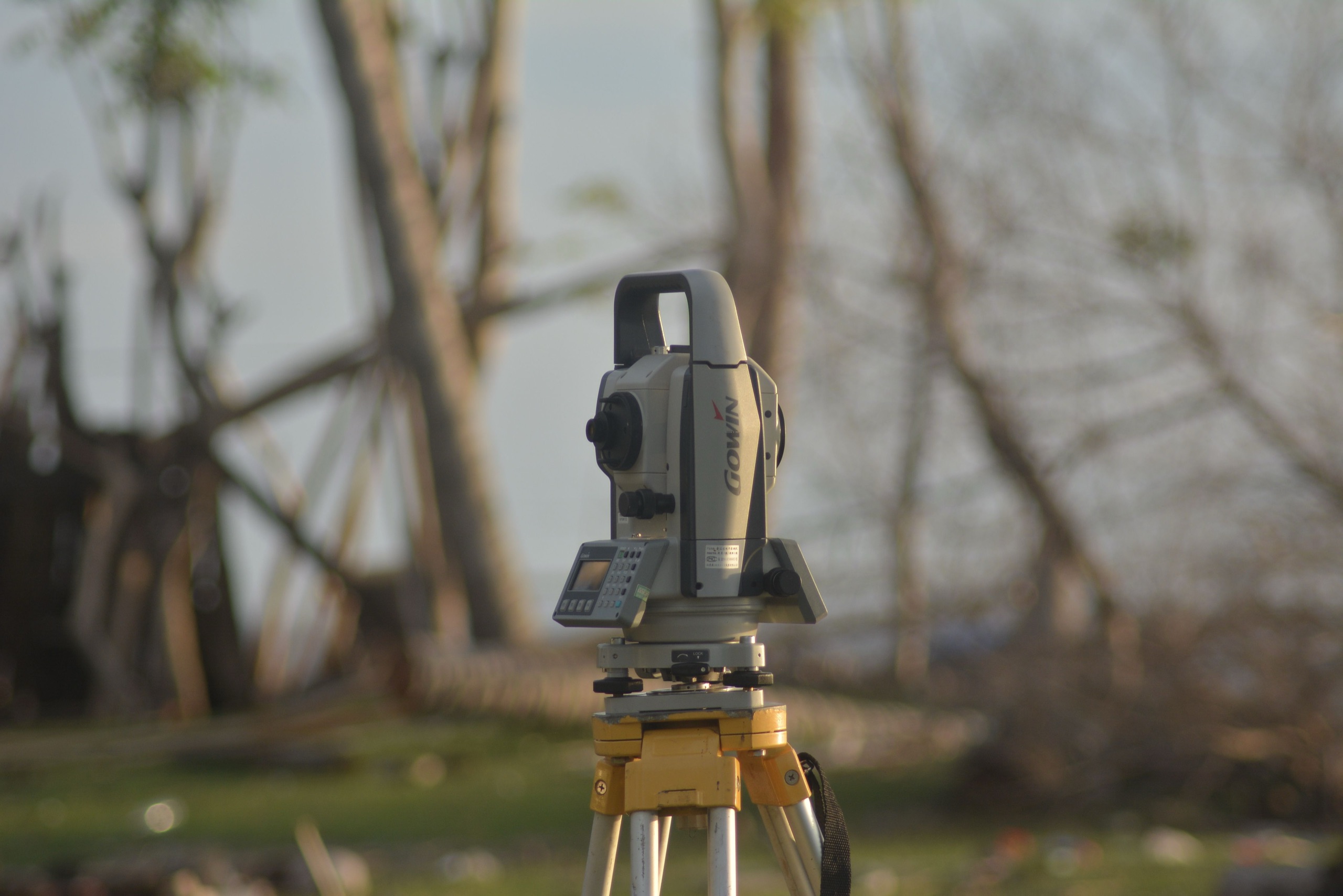 A survey total station on a tripod at a homesite