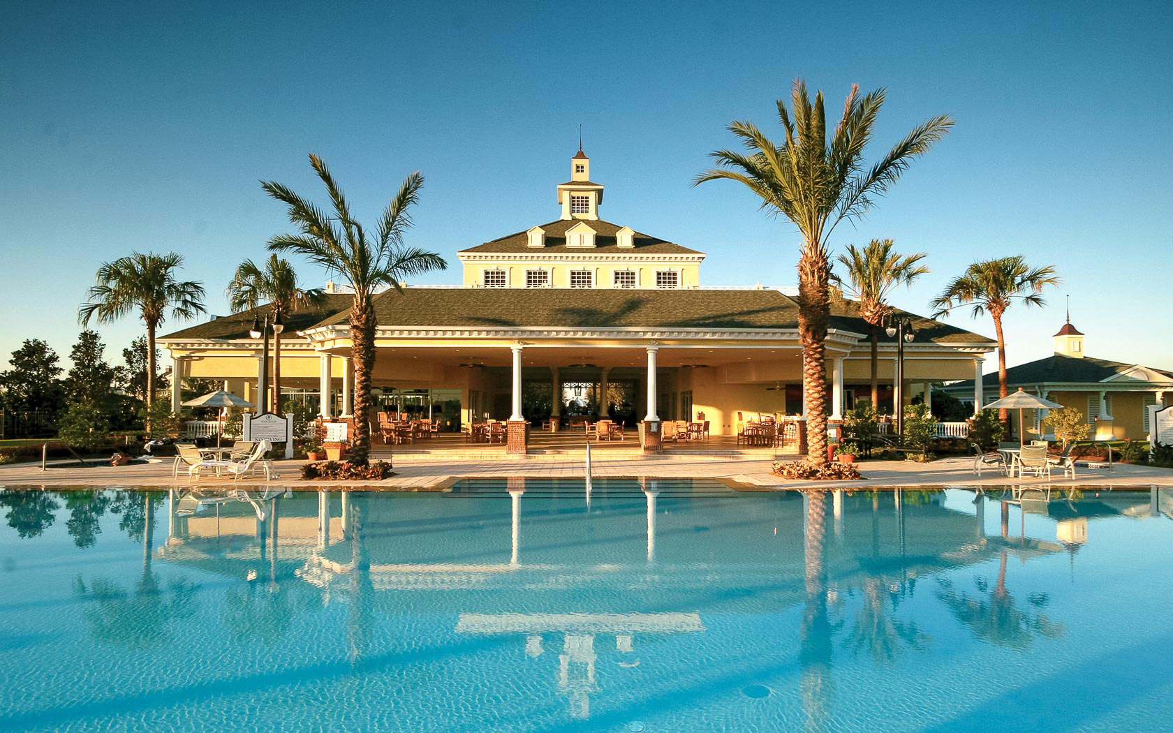 The Reunion clubhouse pool at golden hour, palms reflected in still water