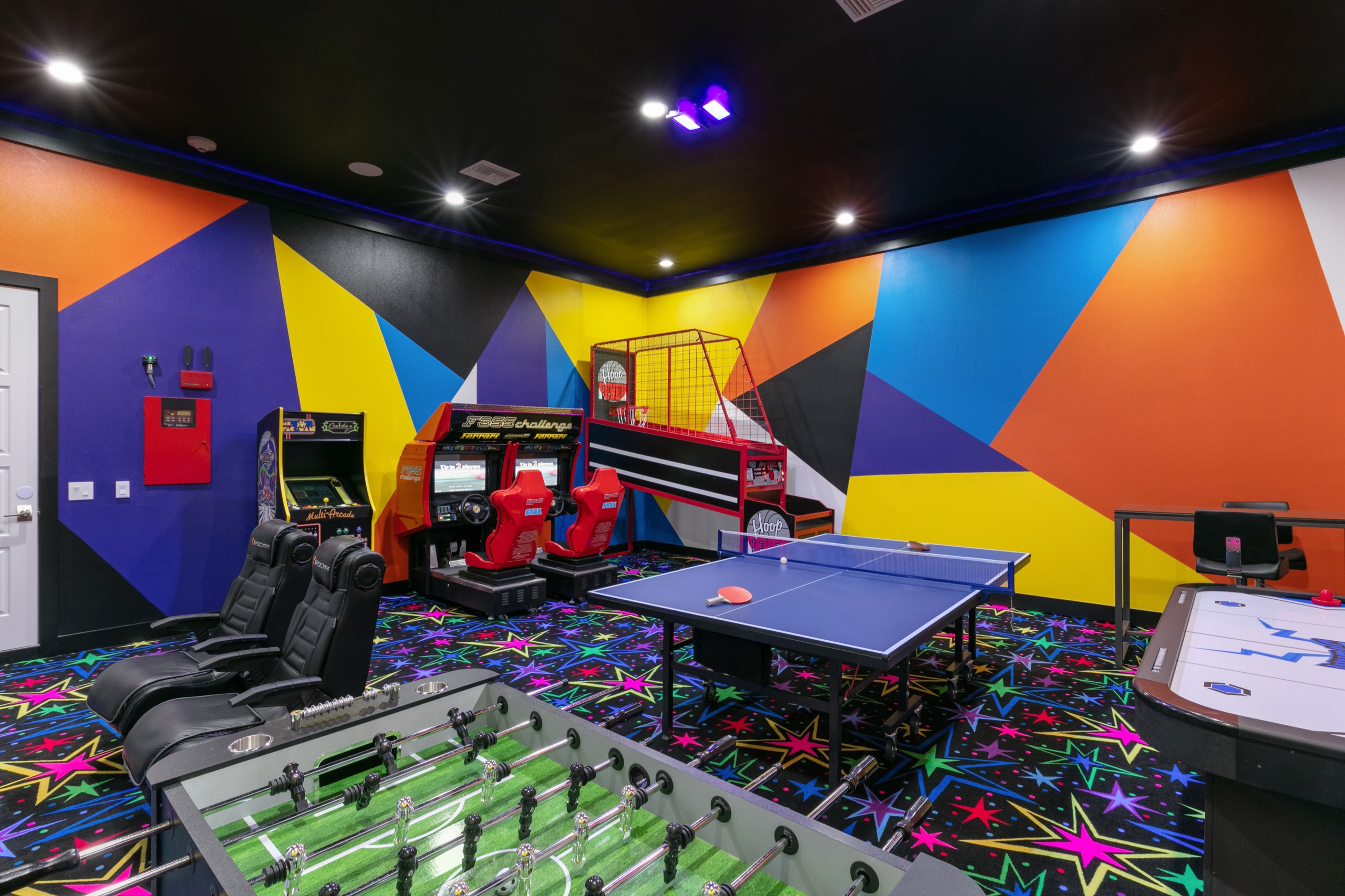 Neon-painted arcade with classic machines and a racing rig