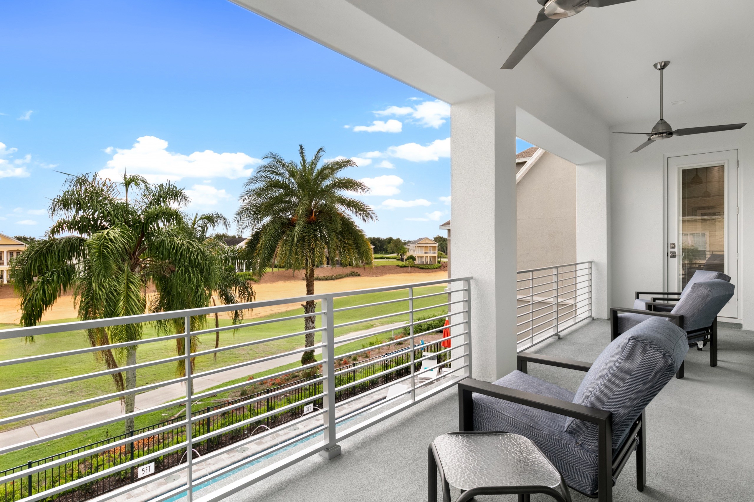 View from the covered upstairs balcony with reclining lounge chairs over the golf fairway and pool