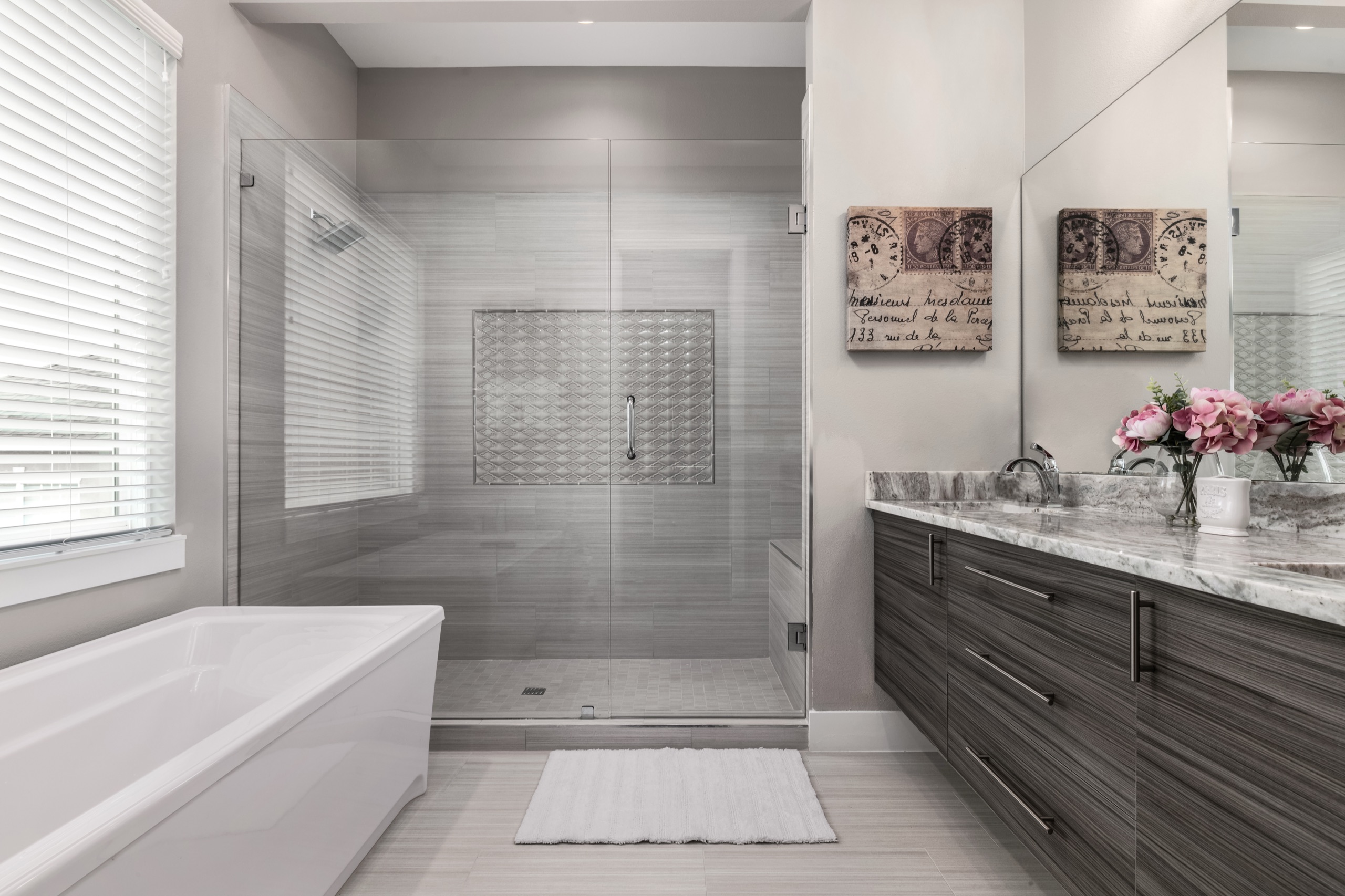 Paris suite bath with a soaking tub, oversized glass shower, gray-wood vanity, and French postage-stamp art