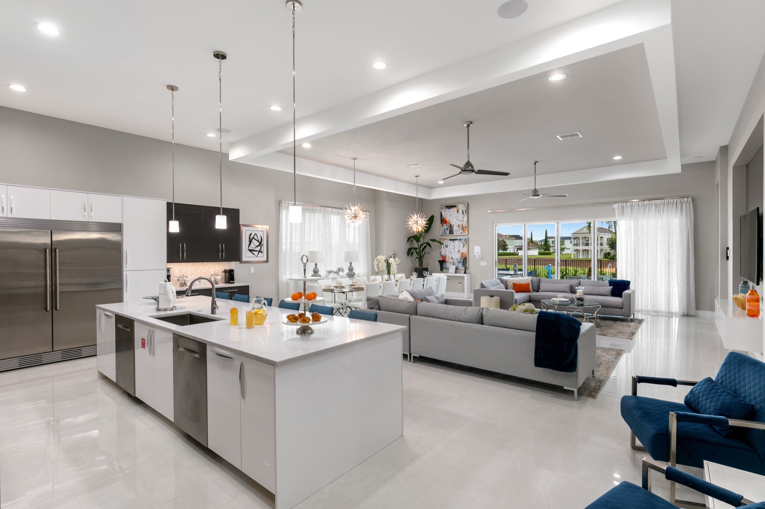Open-plan great room with the white island kitchen flowing to the sectionals and dining beyond