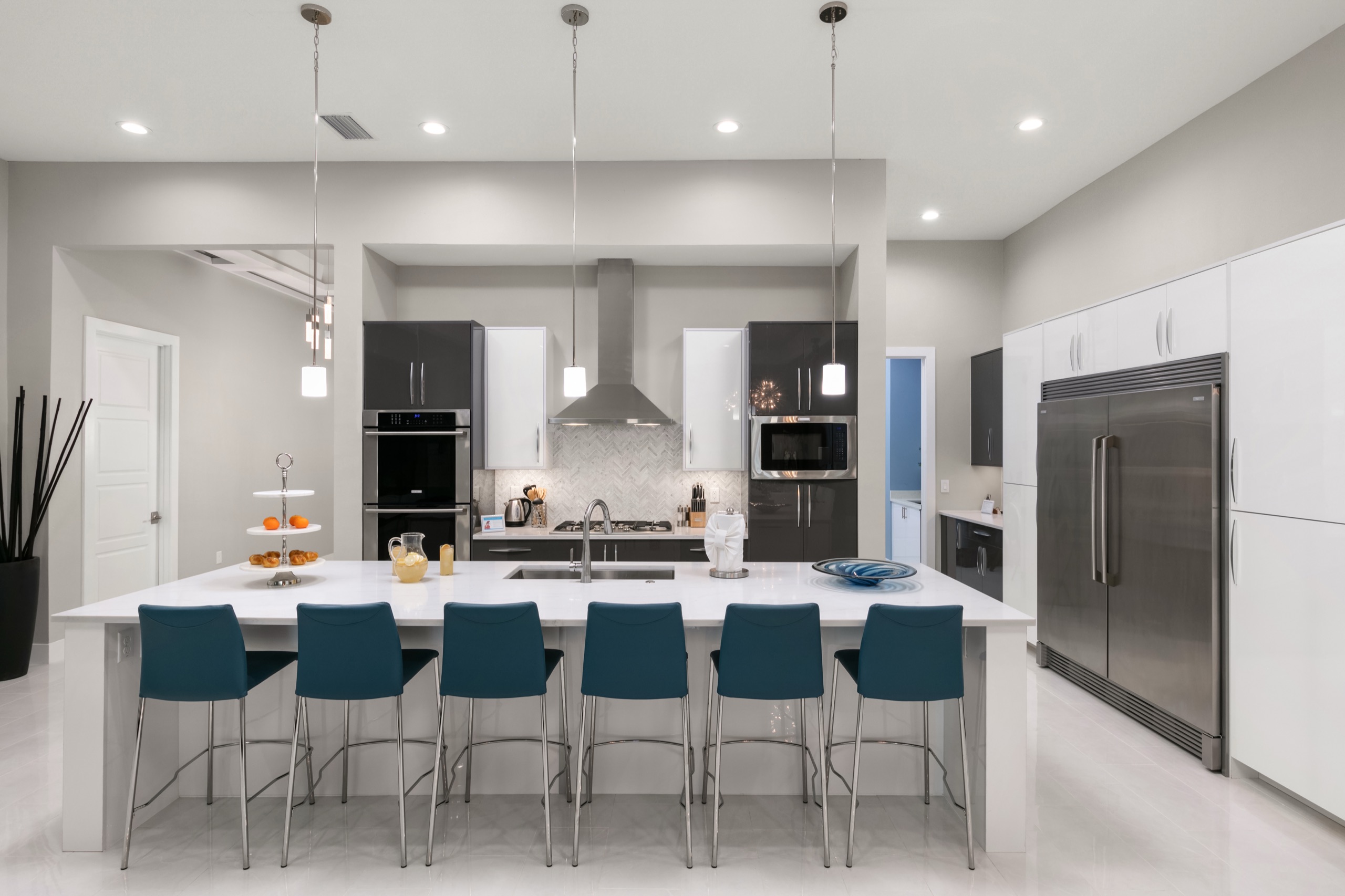 Kitchen island with six blue counter stools beneath pendant lighting