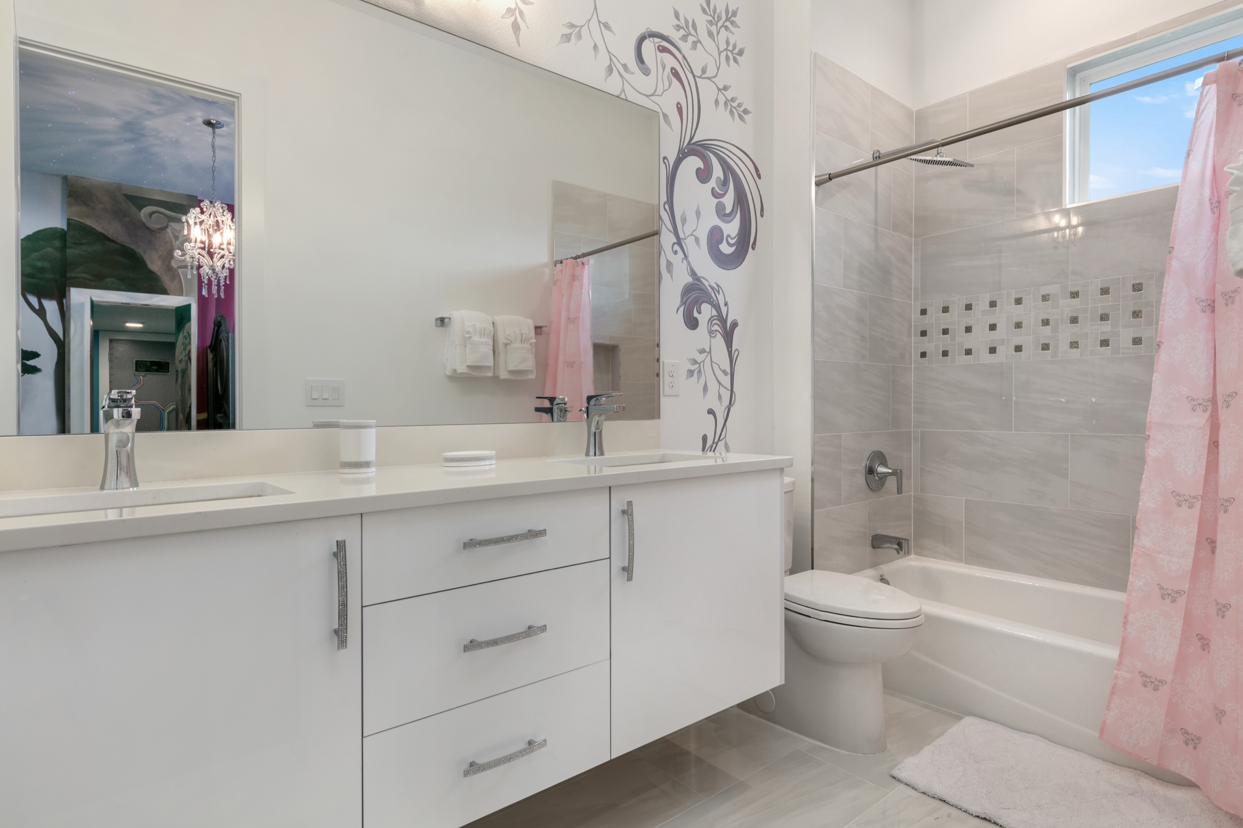 Children's bath with a floral mural, double vanity, and a pink shower curtain