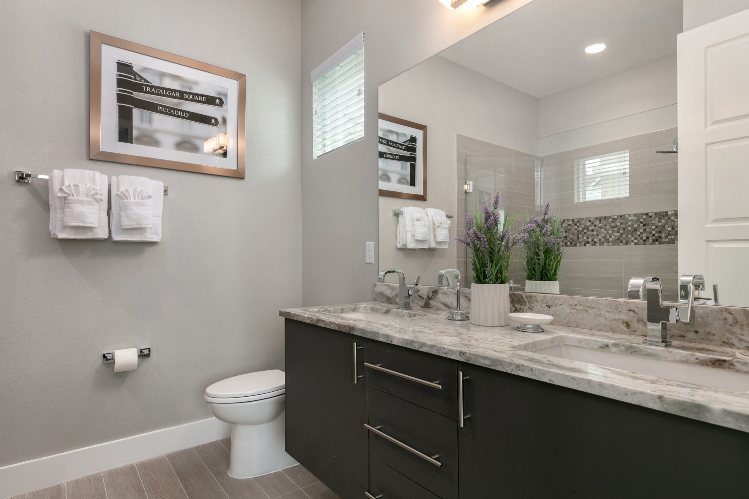 London suite bath with a dark floating vanity, granite counter, and framed Trafalgar Square street-sign art