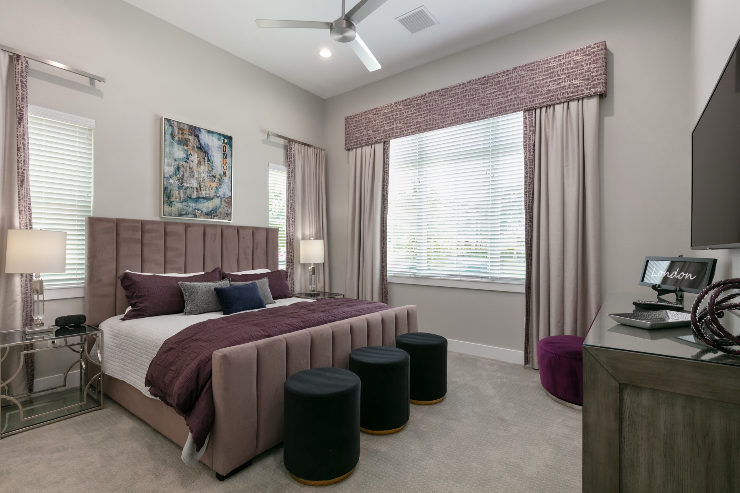London suite with a channel-tufted taupe bed, plum bedding, and a valance-framed window