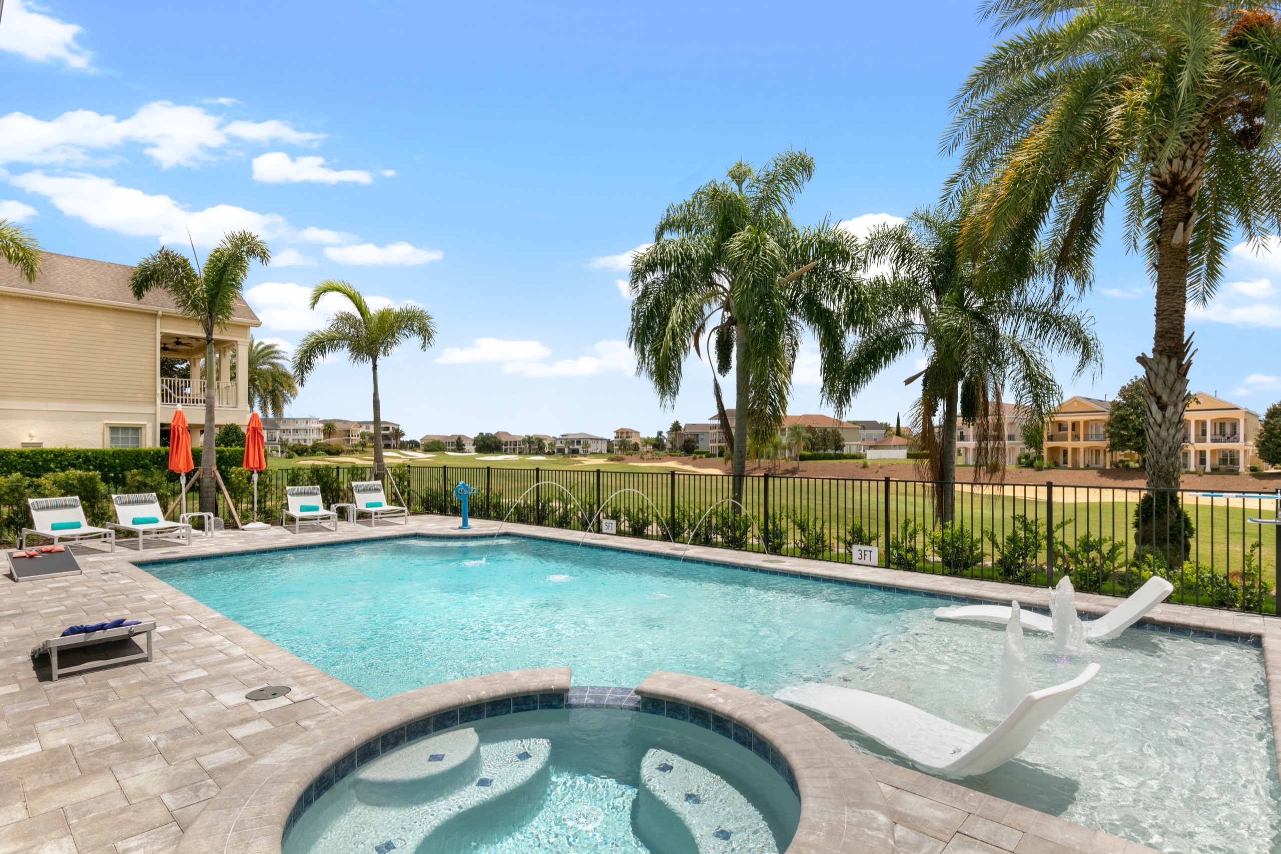 Pool with in-water loungers and raised spa looking across the fence to the fairway