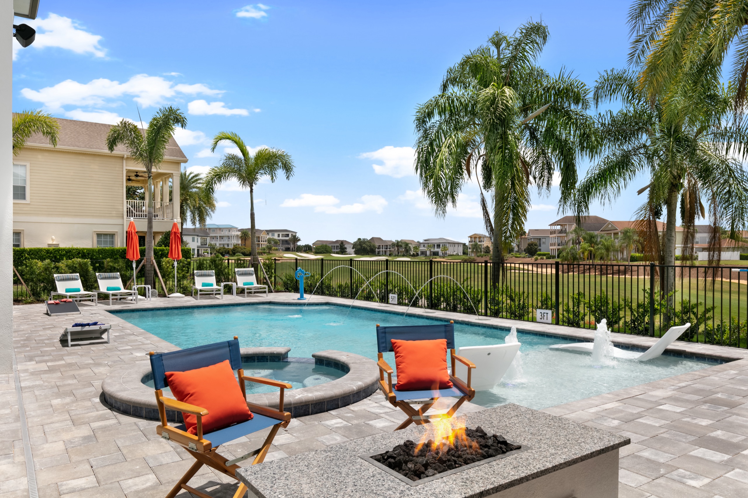 Fire-pit lounge with orange director's chairs beside the pool
